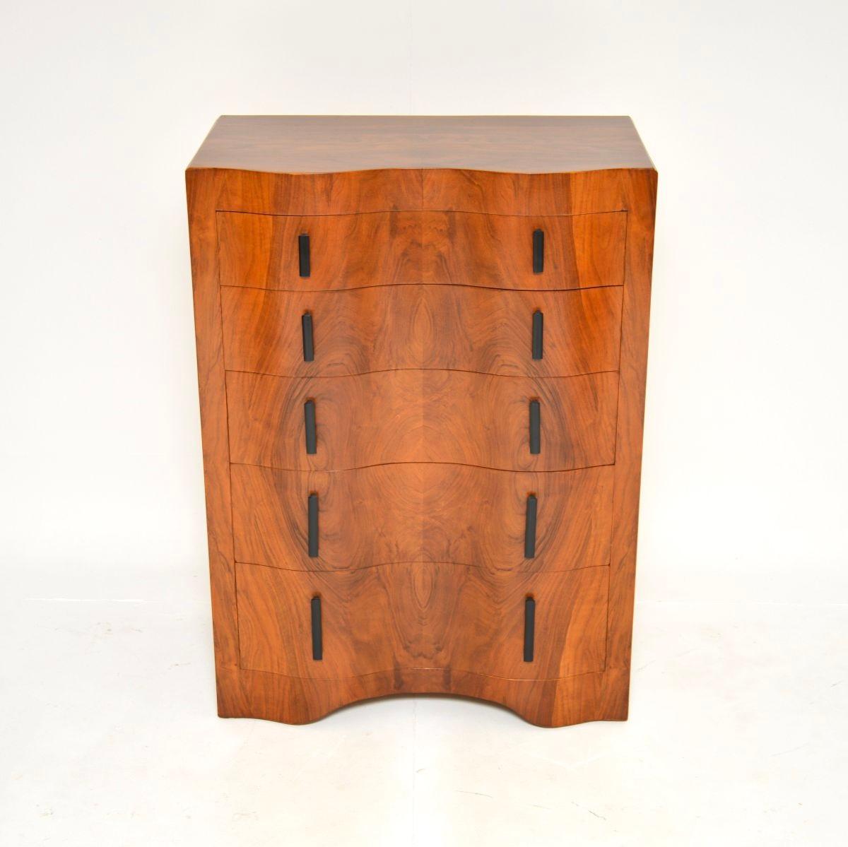 Cette magnifique commode en noyer figuré de style Art Déco a été fabriquée en Angleterre et date des années 1930.

Il est de grande taille et de très bonne qualité, avec une forme serpentine inhabituelle et élégante sur le devant. Les tiroirs