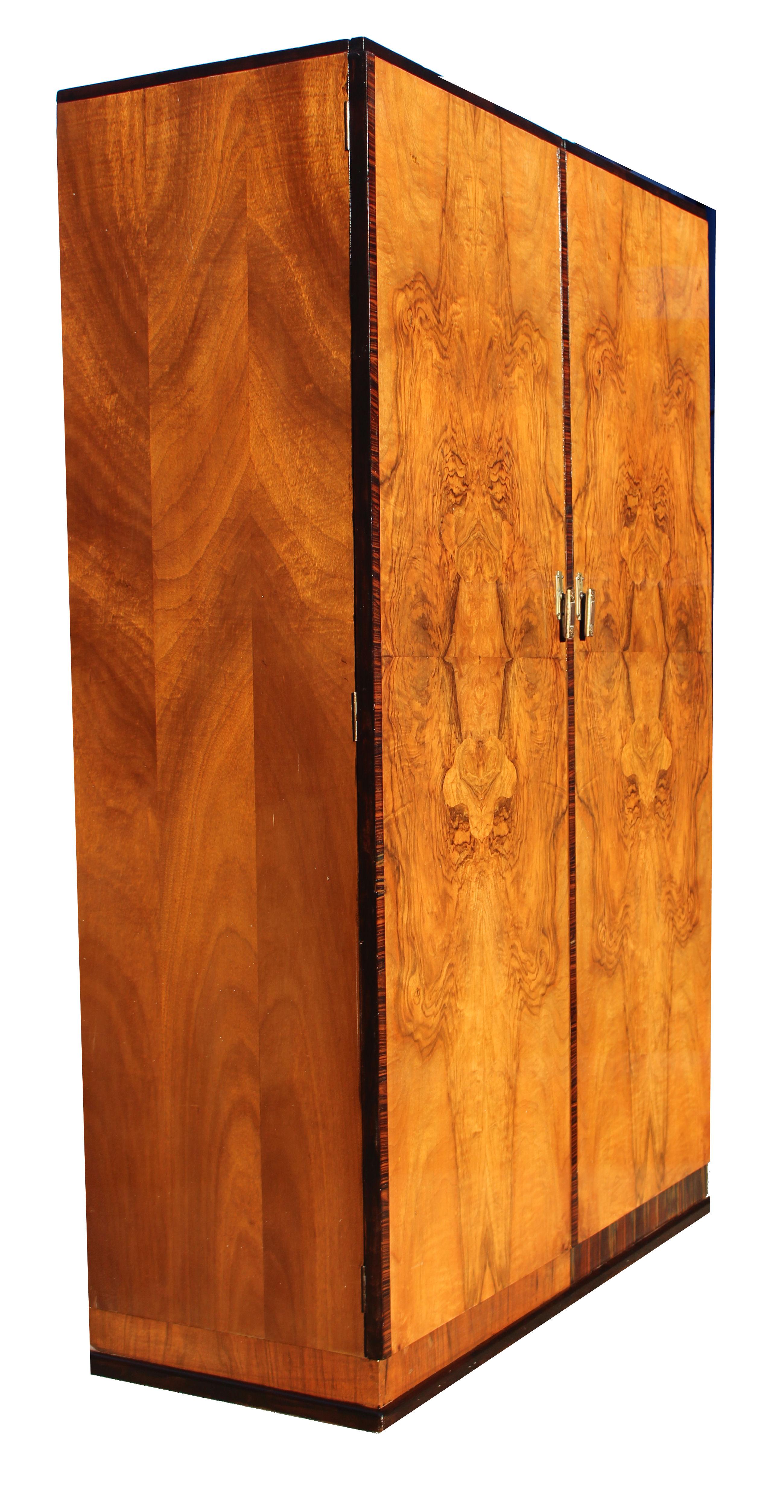 For your consideration is this very striking and imposing Art Deco double wardrobe with a modernist slant. The veneers are wonderful offering light and dark tones. Book paged walnut veneered doors with Macassar banding to the edges and plinth. This