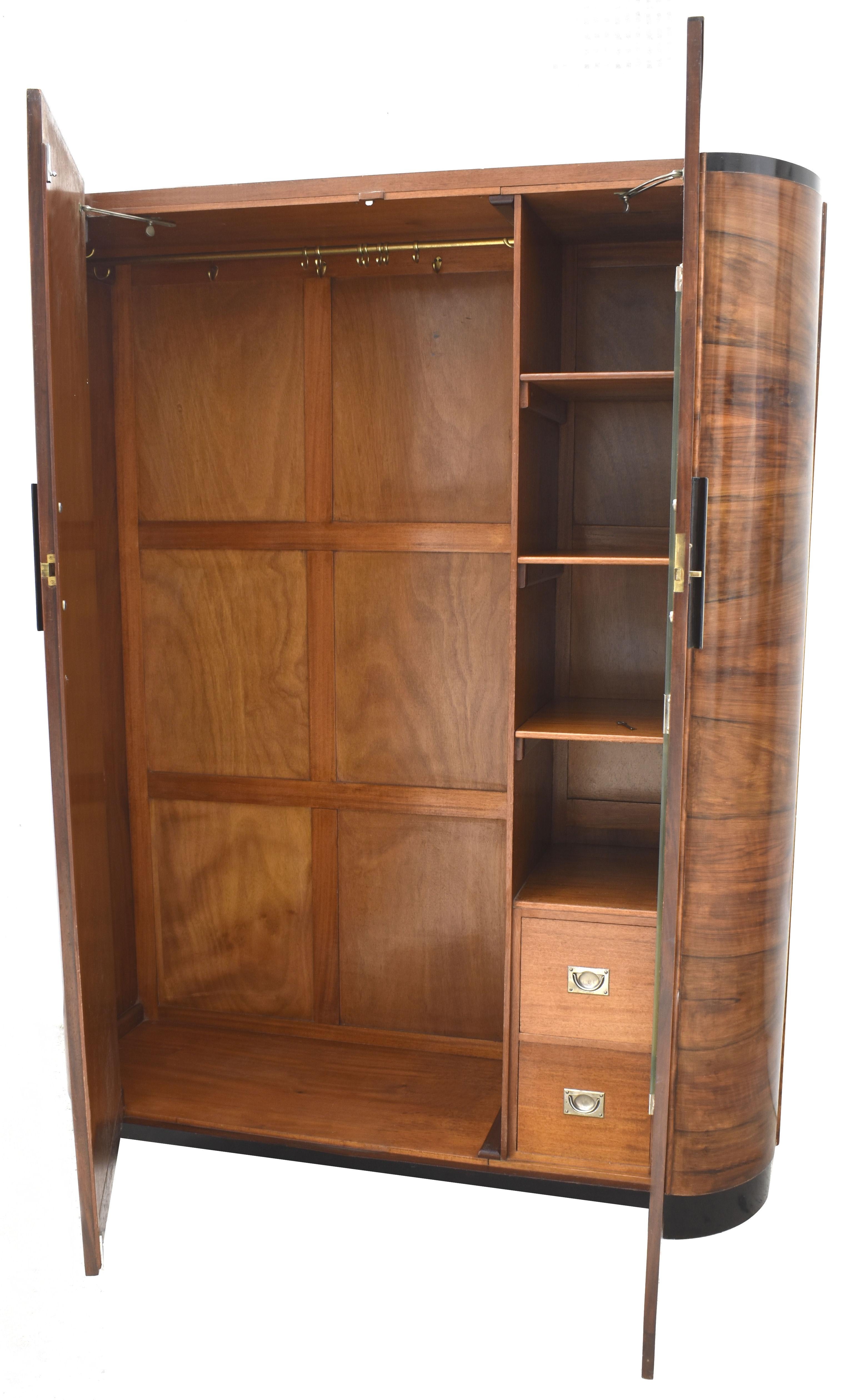 For your consideration is this very striking and imposing Art Deco double wardrobe with a modernist slant. The veneers are wonderful offering light and dark tones. Book paged walnut veneered doors with wide round shoulders that accented by ebonized