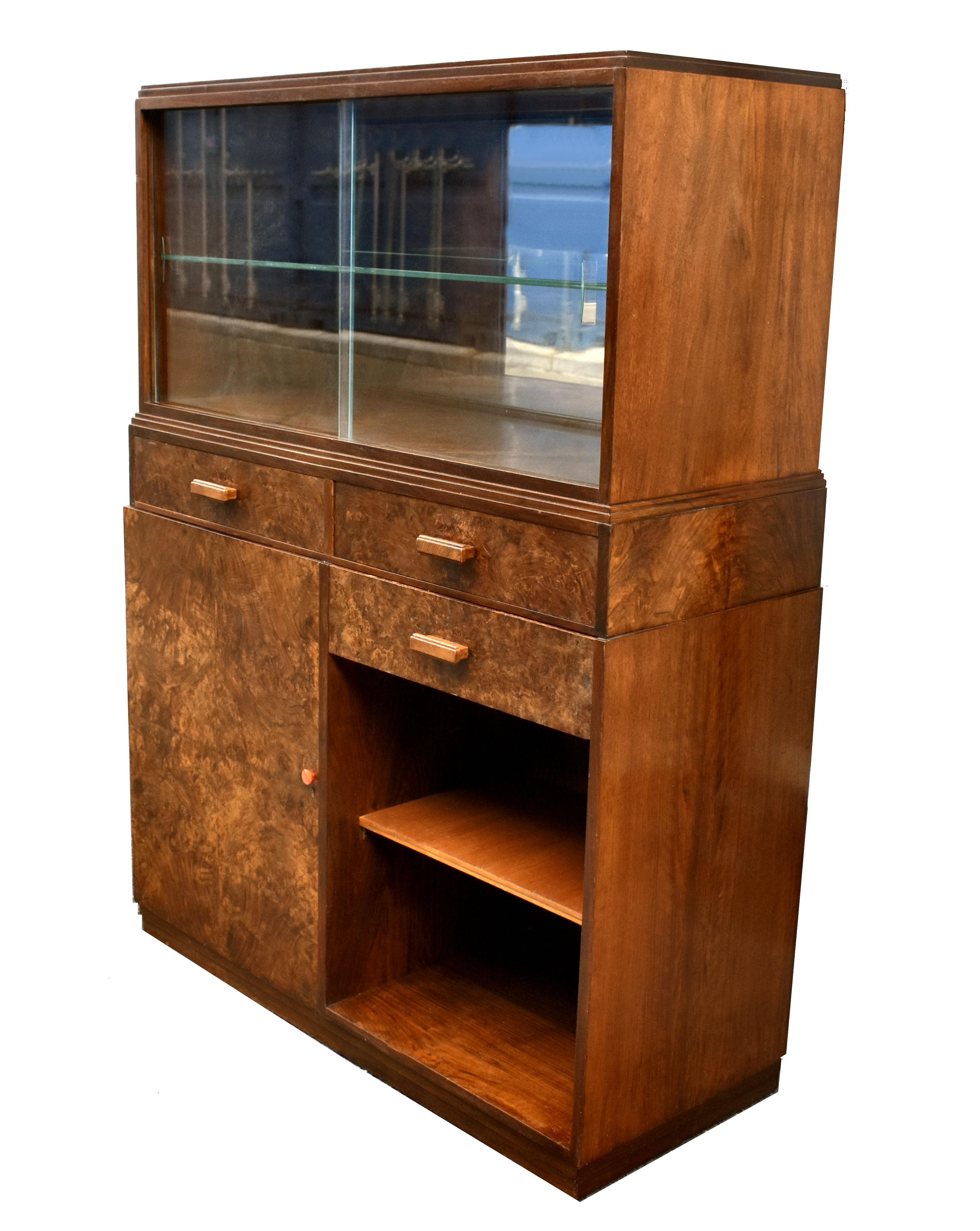 Nous vous présentons ce meuble à boissons anglais Art déco des années 1930, d'une grande élégance. Un meuble fabuleux, non seulement attrayant, mais aussi très fonctionnel. La partie supérieure est dotée de deux portes coulissantes en verre