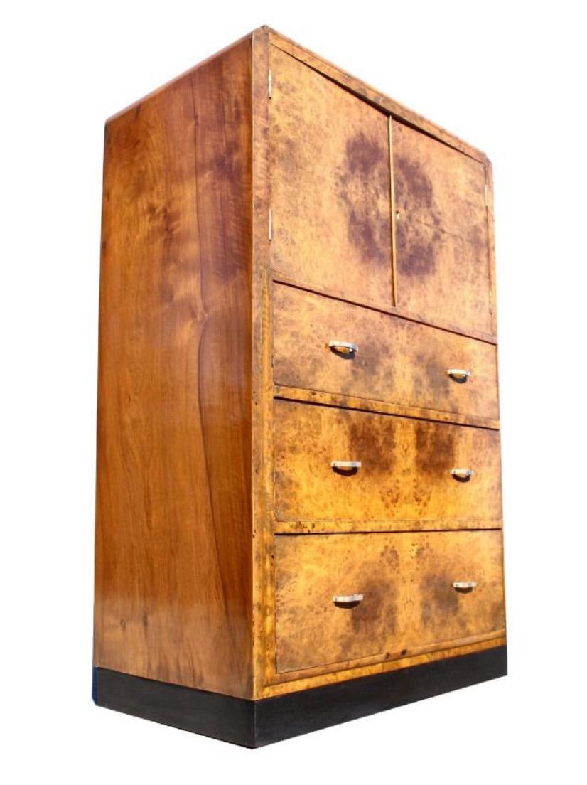 For your consideration is this English Art Deco honey coloured walnut two-door, three drawer single-piece tallboy, circa 1930, boasting stunning mirror matched veneers and in excellent original condition. All resting on a ebonised plinth. The