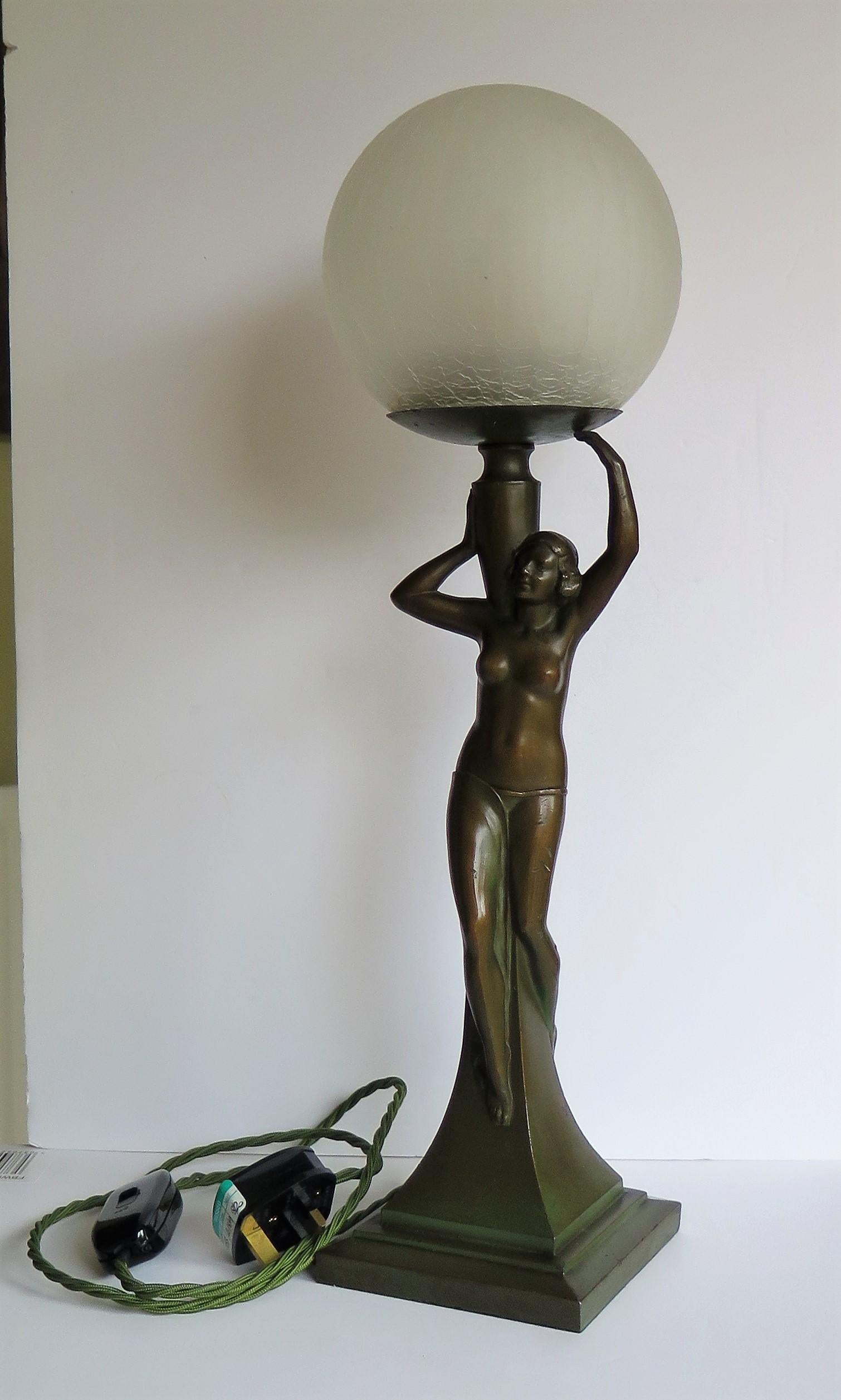 This is a stunning figurine table lamp of a water Carrier Lady Figurine sculpture made of Spelter in France, circa 1930.

The figurine is made of spelter with good detail. It has developed a lovely patinated bronze colour with a green