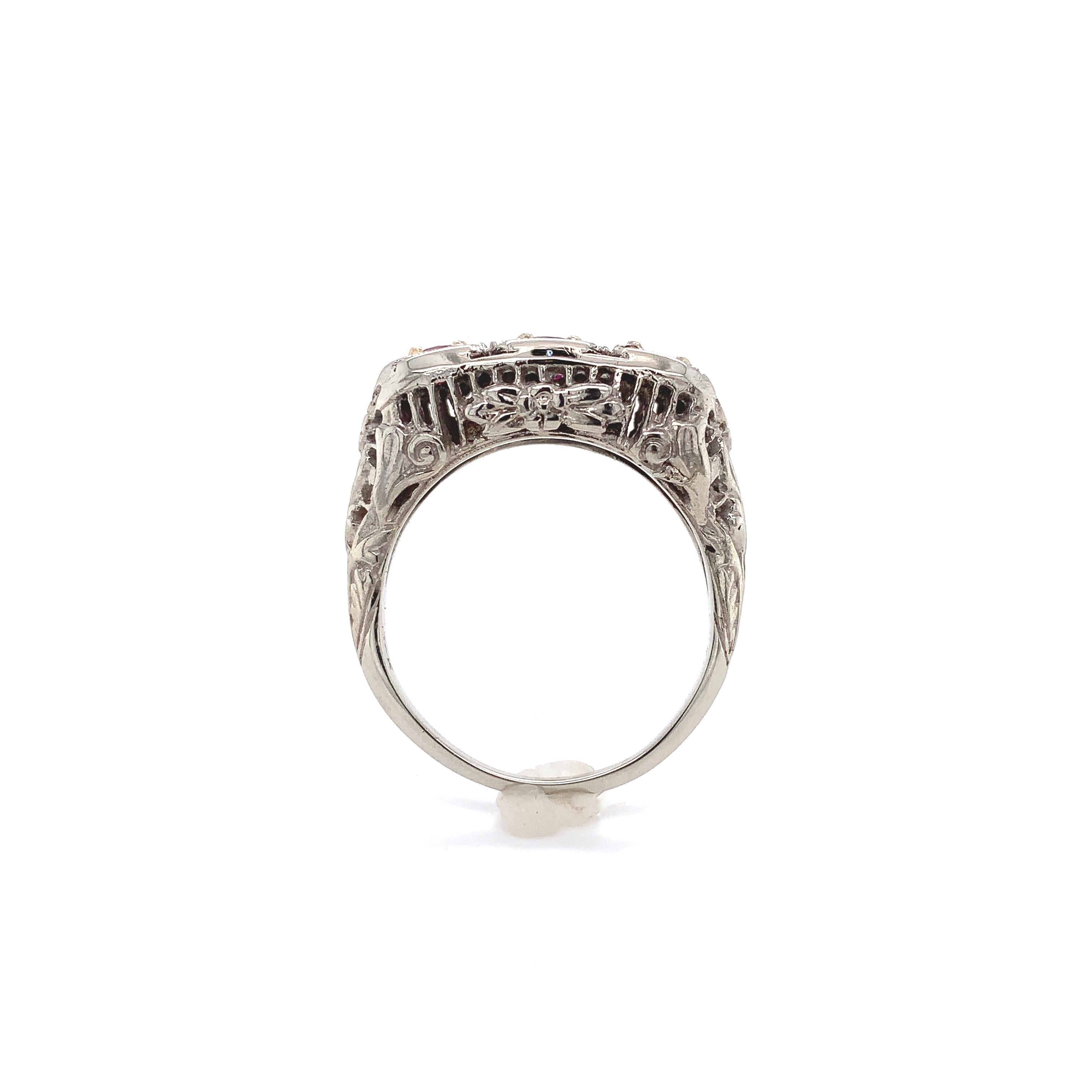Anello Art Deco in oro bianco 14K con rubino in filigrana. L'anello presenta 3 autentici rubini rotondi rosa-rosso estratti in terra per un peso totale di 0,80 carati. I rubini misurano circa 3,5 mm. L'anello si adatta a un dito di taglia 7,75. Pesa