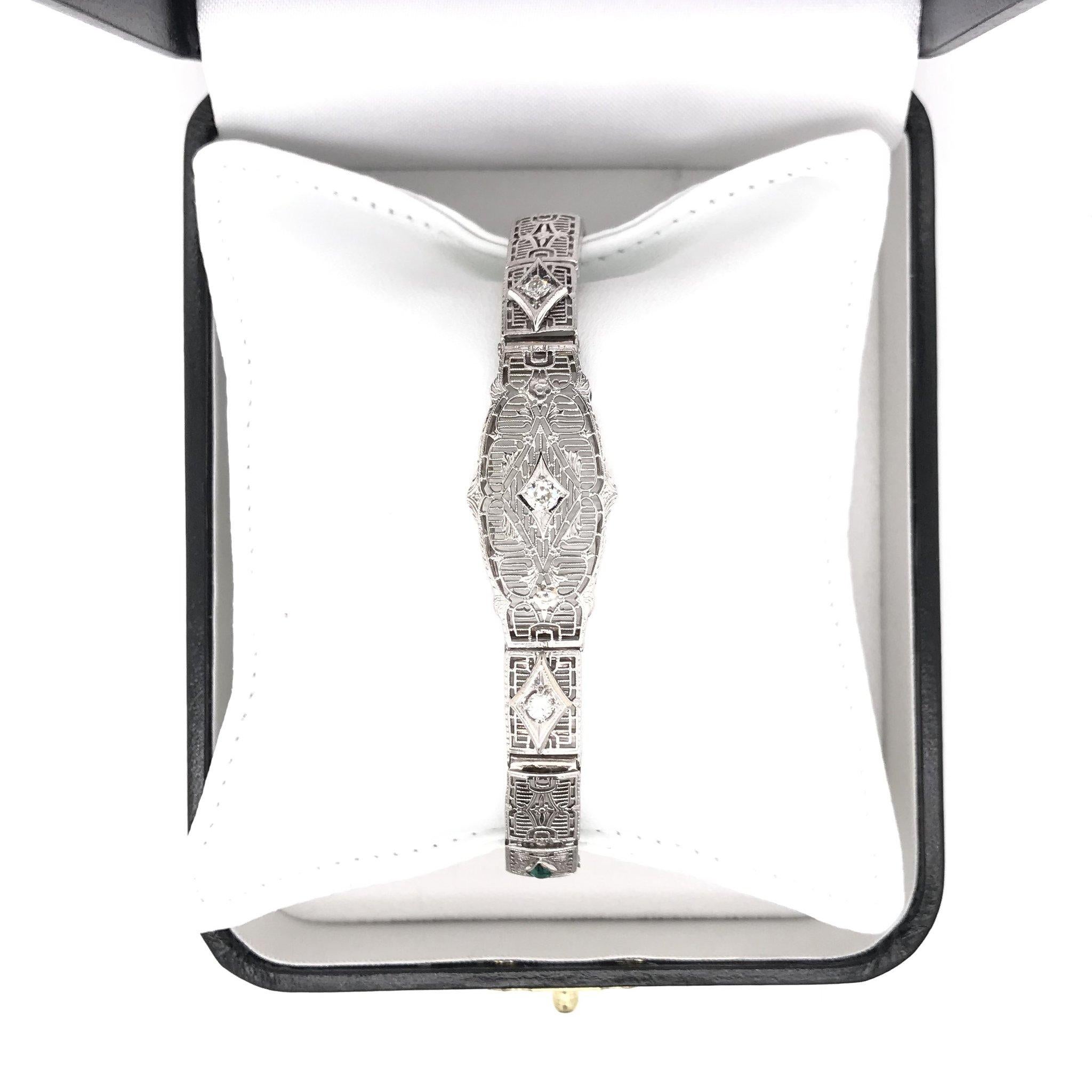 This antique piece was handcrafted sometime during the Art Deco design period ( 1920-1940 ). The setting is 14k white gold and the links feature intricately beautiful filigree. The bracelet features three small sparkling diamond accents as well as