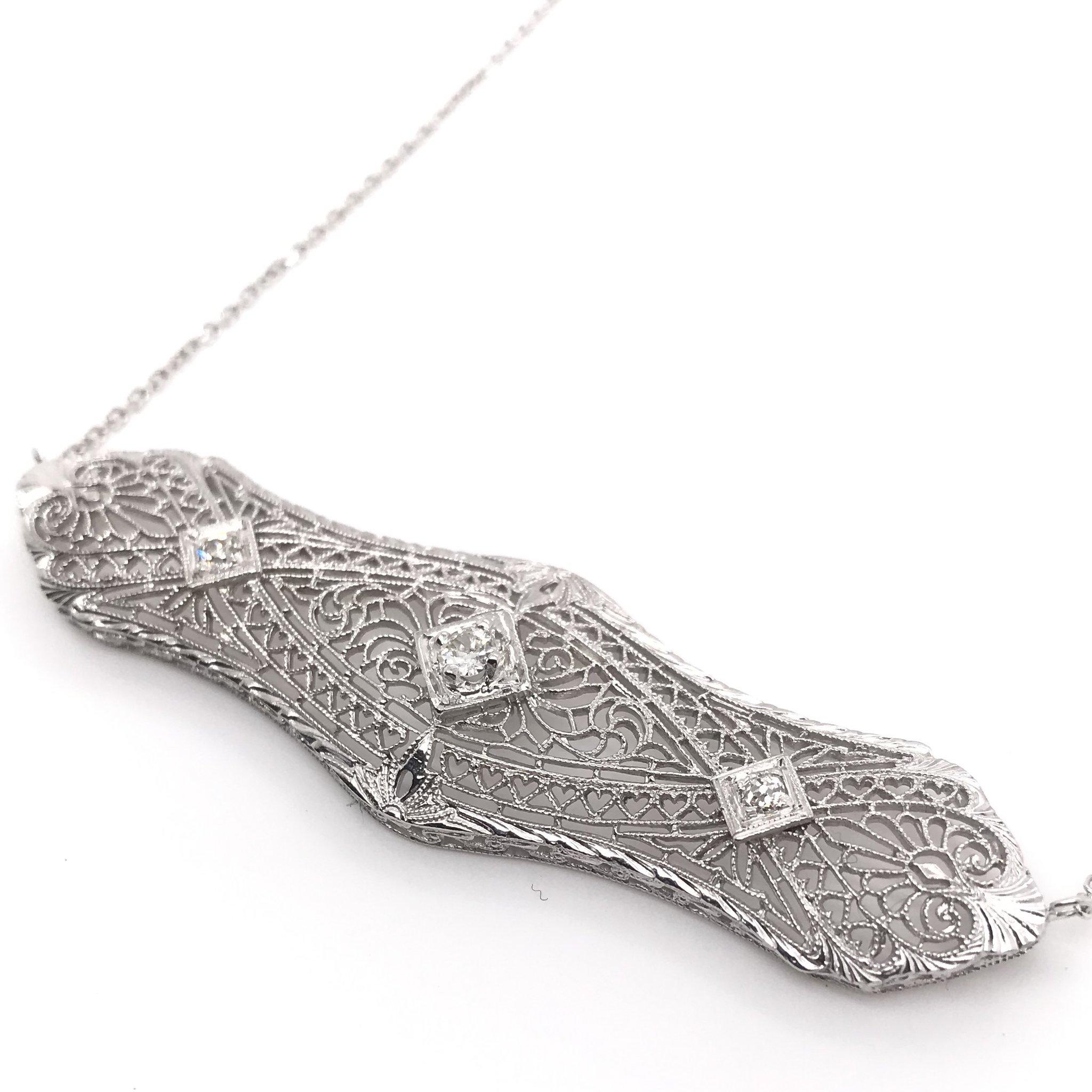 This piece is an antique revision made from reclaimed antique materials. This necklace was originally an antique filigree brooch handcrafted sometime during the Art Deco design period ( 1920-1940 ). The pendant features three sparkling diamond