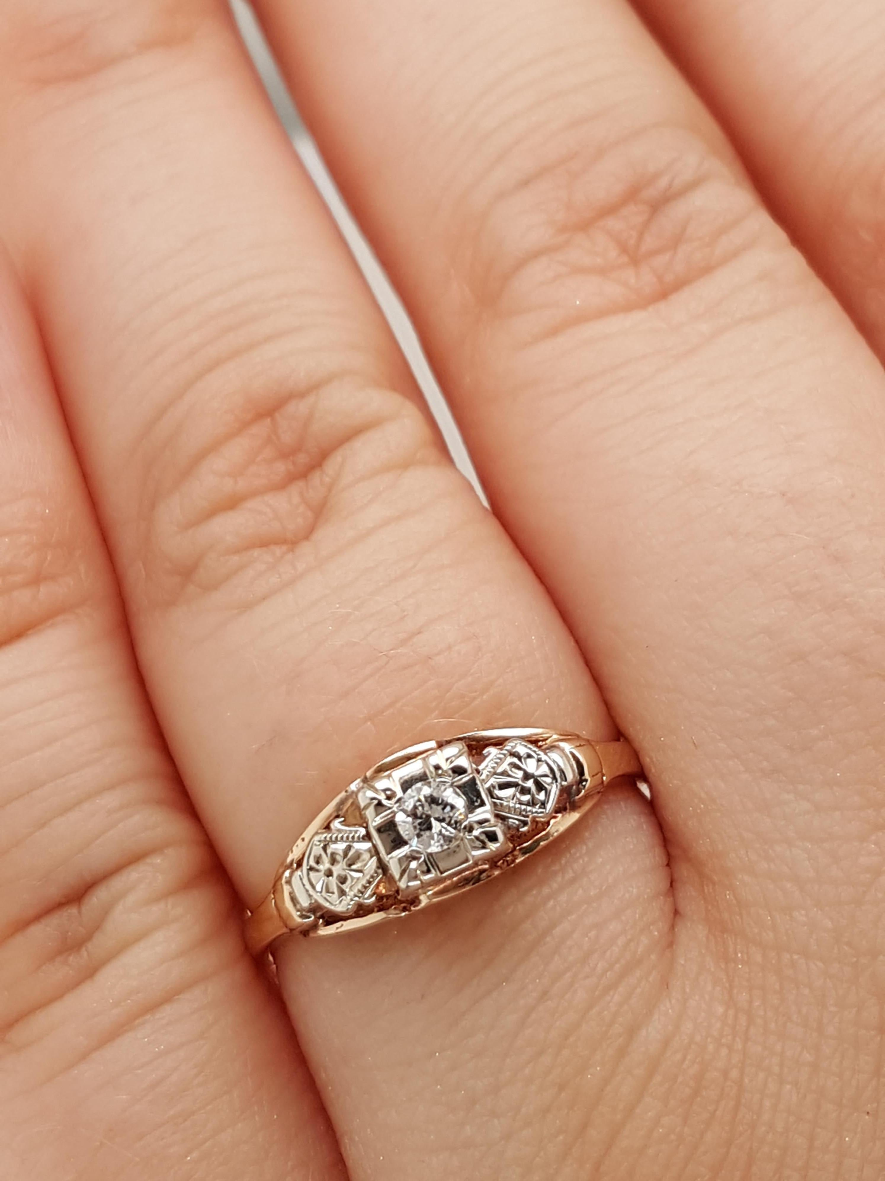This Art Deco solitaire is a fine example of a filigree solitaire engagement ring crafted in 14 karat white 7 yellow gold. The 0.07 ct old European cut diamond is held high in four prongs showcasing the solitaire from all sides! Flowing down from