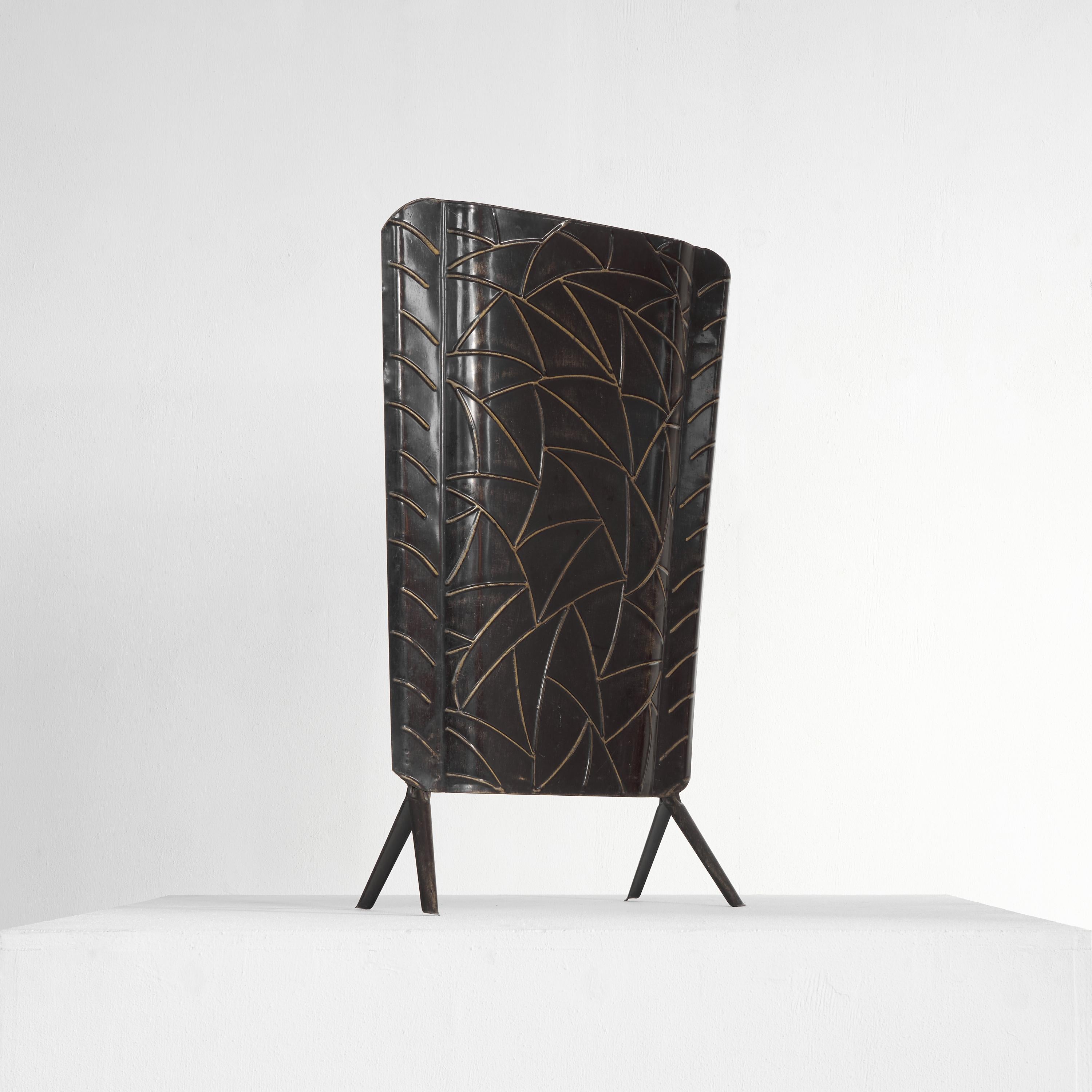 Art Deco fire screen in tin, 1940s. 

This is a very decorative fire screen made out of tin, featuring a wonderful playful design resembling leaves or feathers in a very abstract way. It features a distinct art deco appearance. Also, the wear and