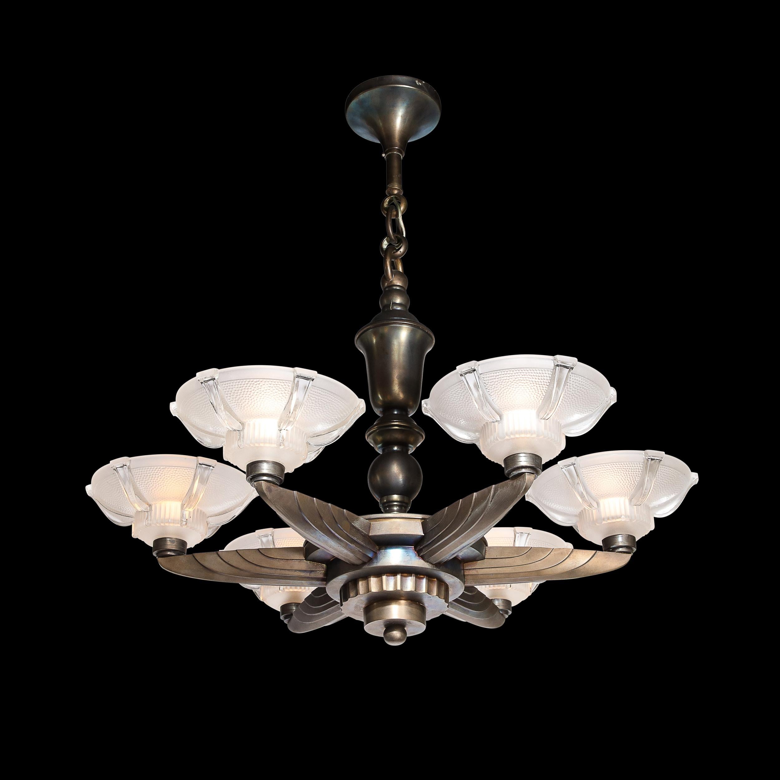 This exquisite Art Deco Machine Age chandelier was realized in France by the legendary atelier of Petitot circa 1935. It features a skyscraper style base with two tiers secured by an orbital finial. The upper tier features dramatically channeled and