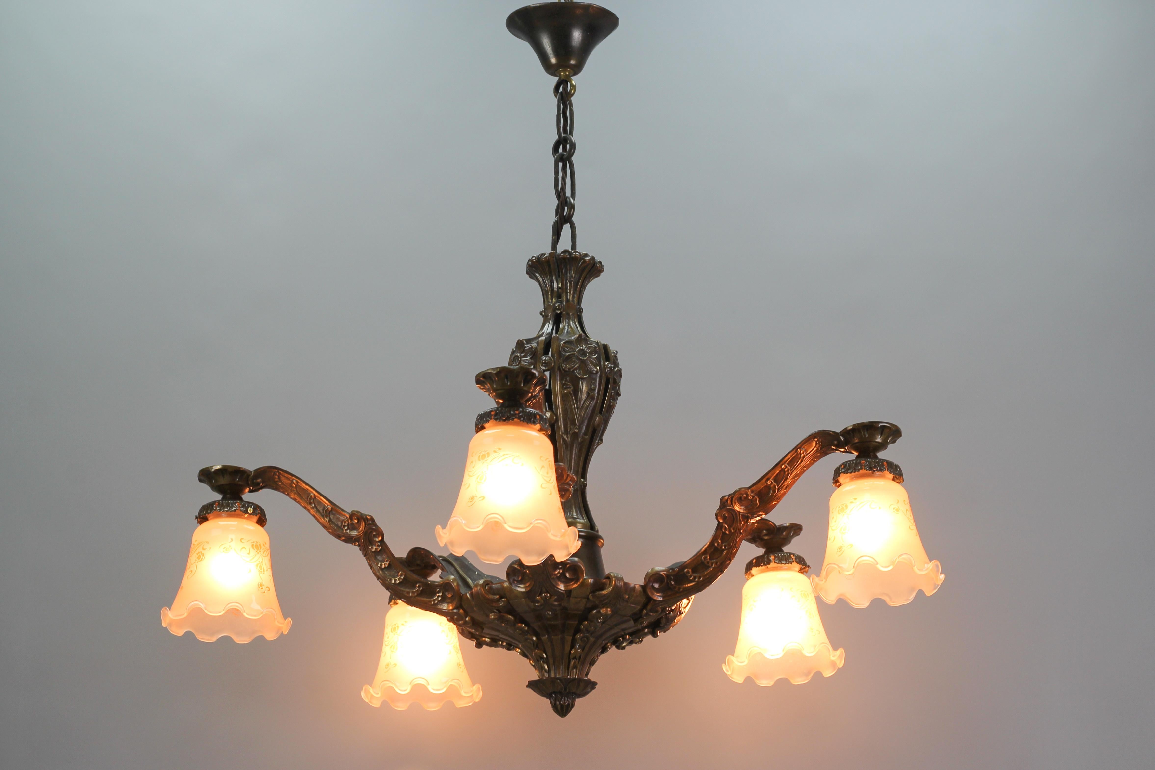 Beautiful French Art Nouveau bronze chandelier from the 1920s. Five bronze arms decorated with flowers and ornaments, each with a tangerine color glass lampshade with floral motifs. The glass lampshades could be from circa the 1950s.
Five sockets