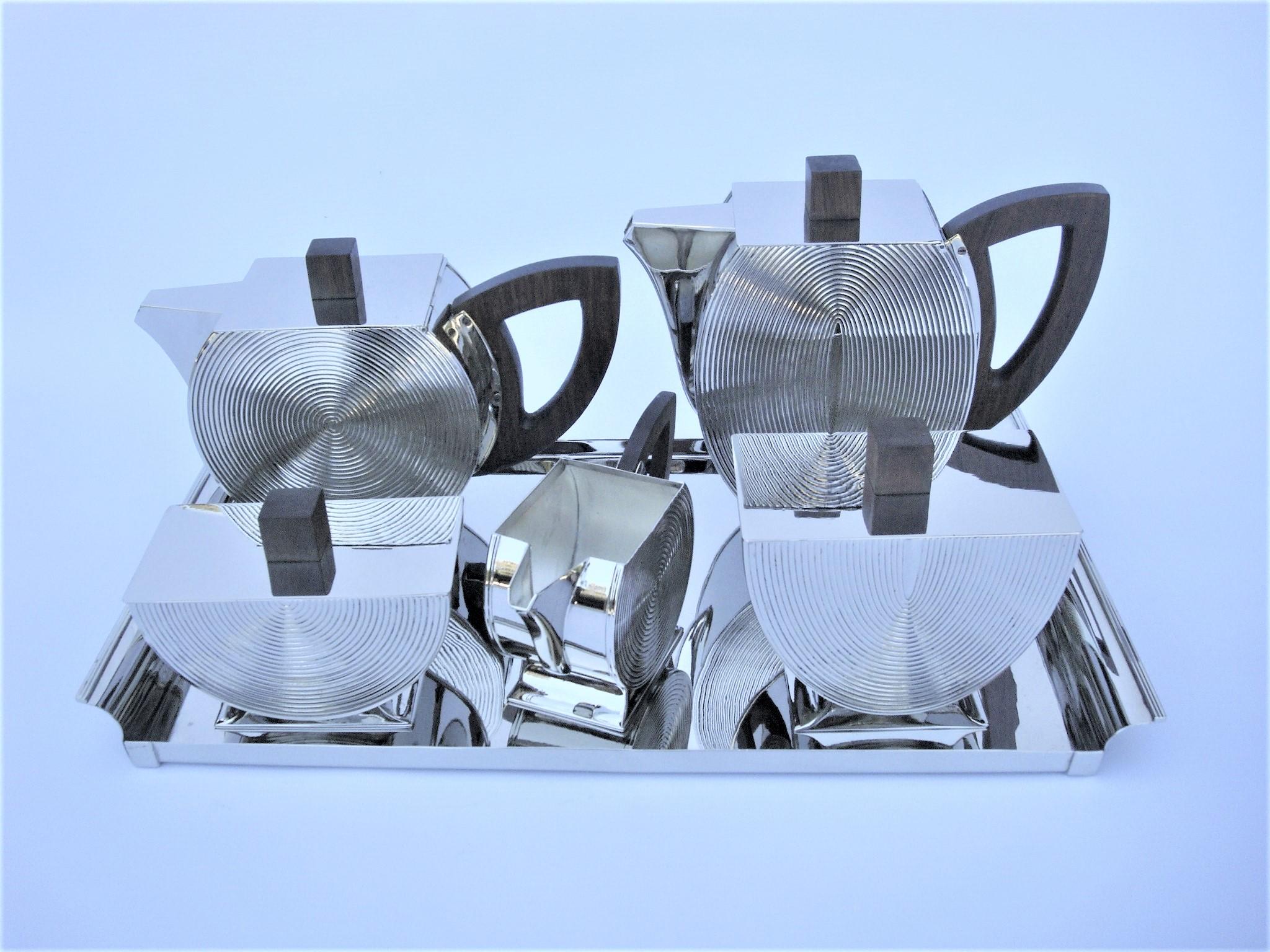A silvered Art Deco five-piece tea and coffee set from the 20th century. The set comprises a teapot, a coffee pot, a creamer and a covered sugar bowl, all with flattened round bodies cut to the top with hinged covers, ear-shaped wooden handles and