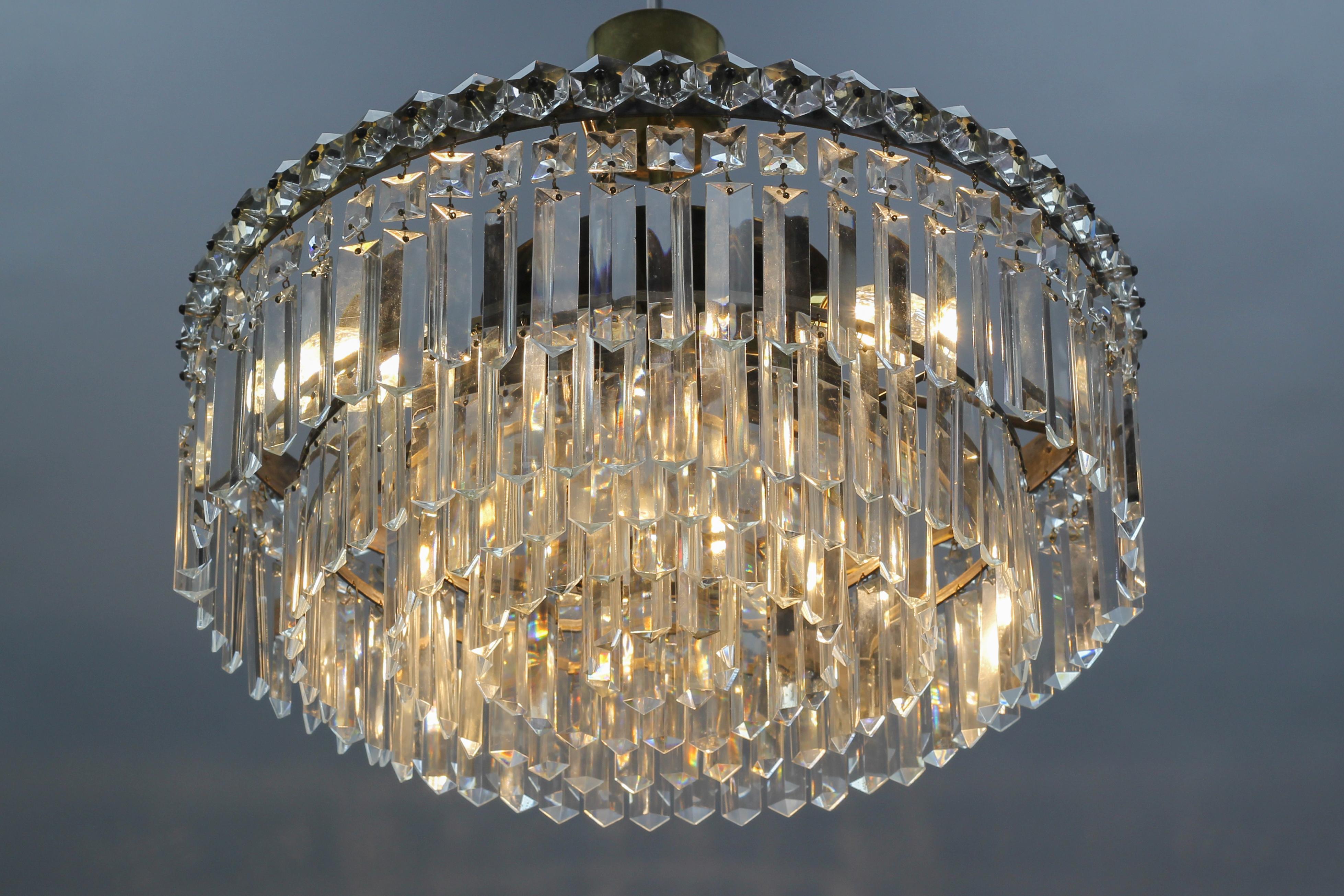 Art Deco style five-tiered three-light crystal glass and brass chandelier from circa 1950s.
This beautiful Art Deco style chandelier in a classic wedding cake form creates with its five cascading layers of crystal glass prisms a sparkling waterfall