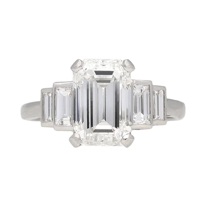 Art Deco flanked solitaire diamond ring. Set to centre with a single rectangular emerald-cut diamond, H colour, VVS1 clarity with an approximate weight of 3.02 carats in an open back claw setting, flanked by four rectangular baguette cut diamonds in