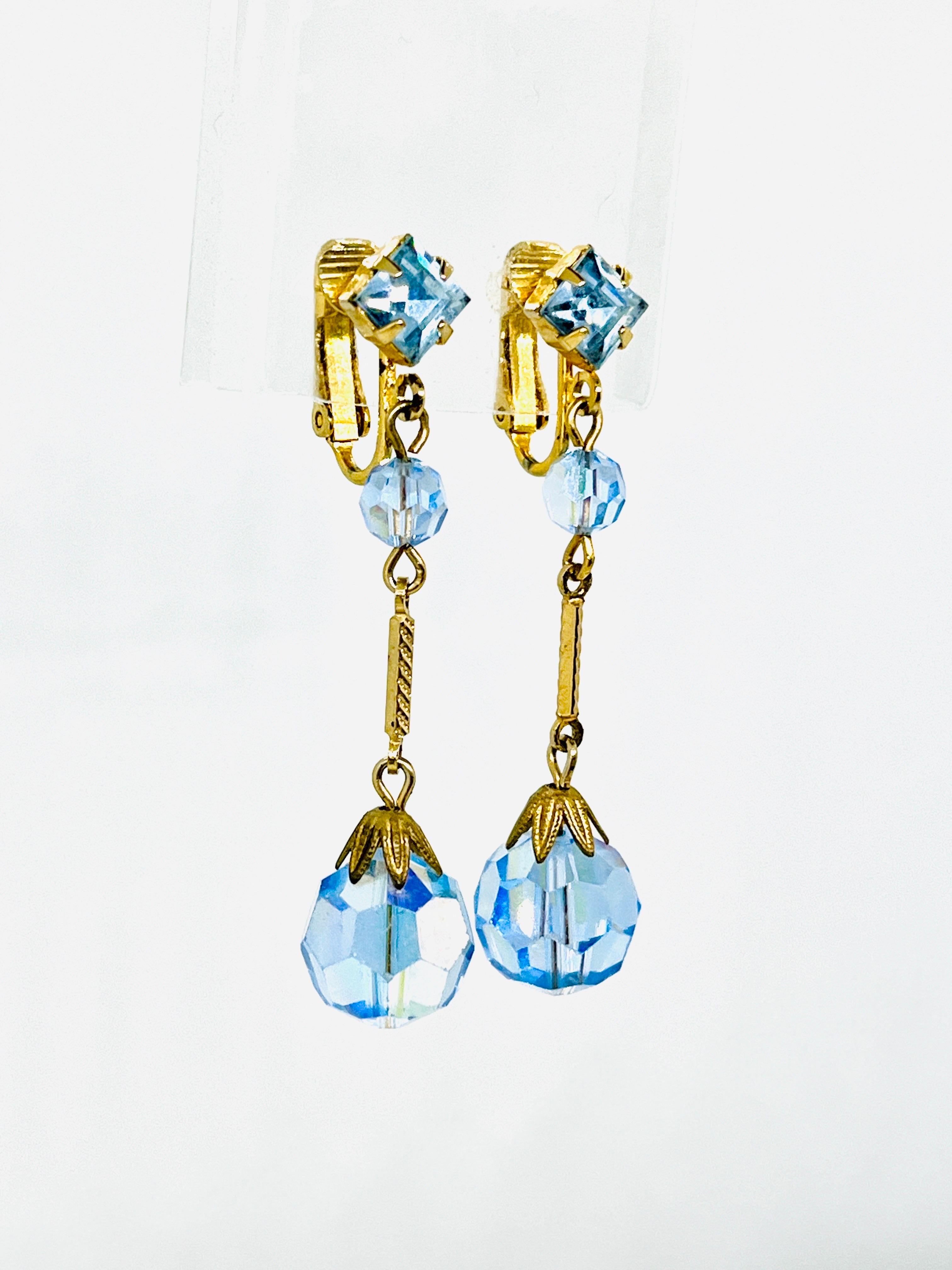 Art Deco Resurgence Flapper Clip Earrings; Sky Blue Faceted AB Glass, Matching Geometric Square Rhinestone, circa 1960s, Polished and Satin Finished Brass. Floral satin floral brass bead cap detail. 

Indicative of the style of the Jazz Age, these