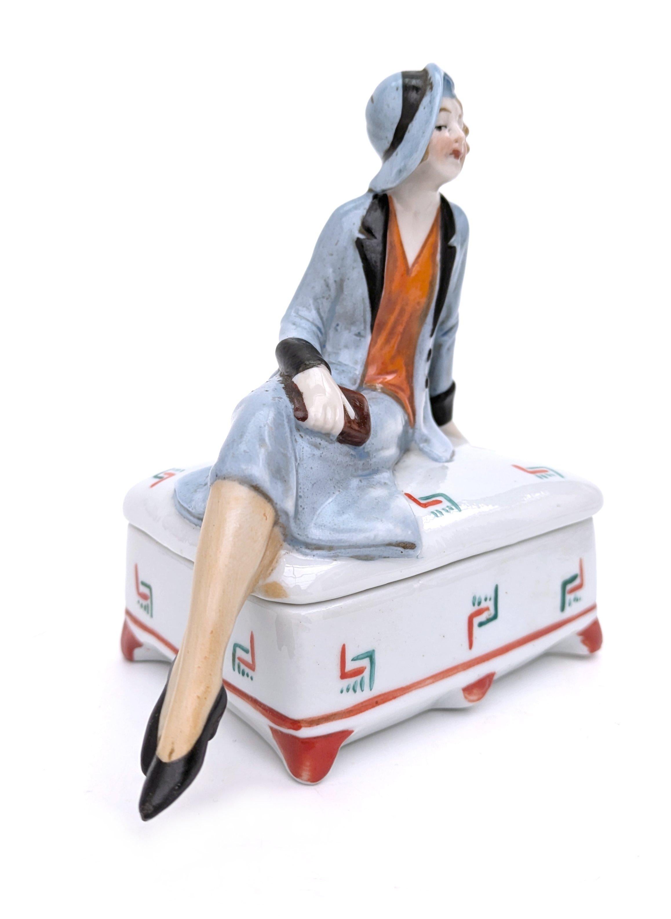 Splendido portacipria in ceramica Art Deco degli anni '30. Un design raro e molto ricercato. L'attenzione per i dettagli è semplicemente meravigliosa, così abilmente dipinta, dalle guance leggermente arrossate alle dita minuscole, tutto in questo