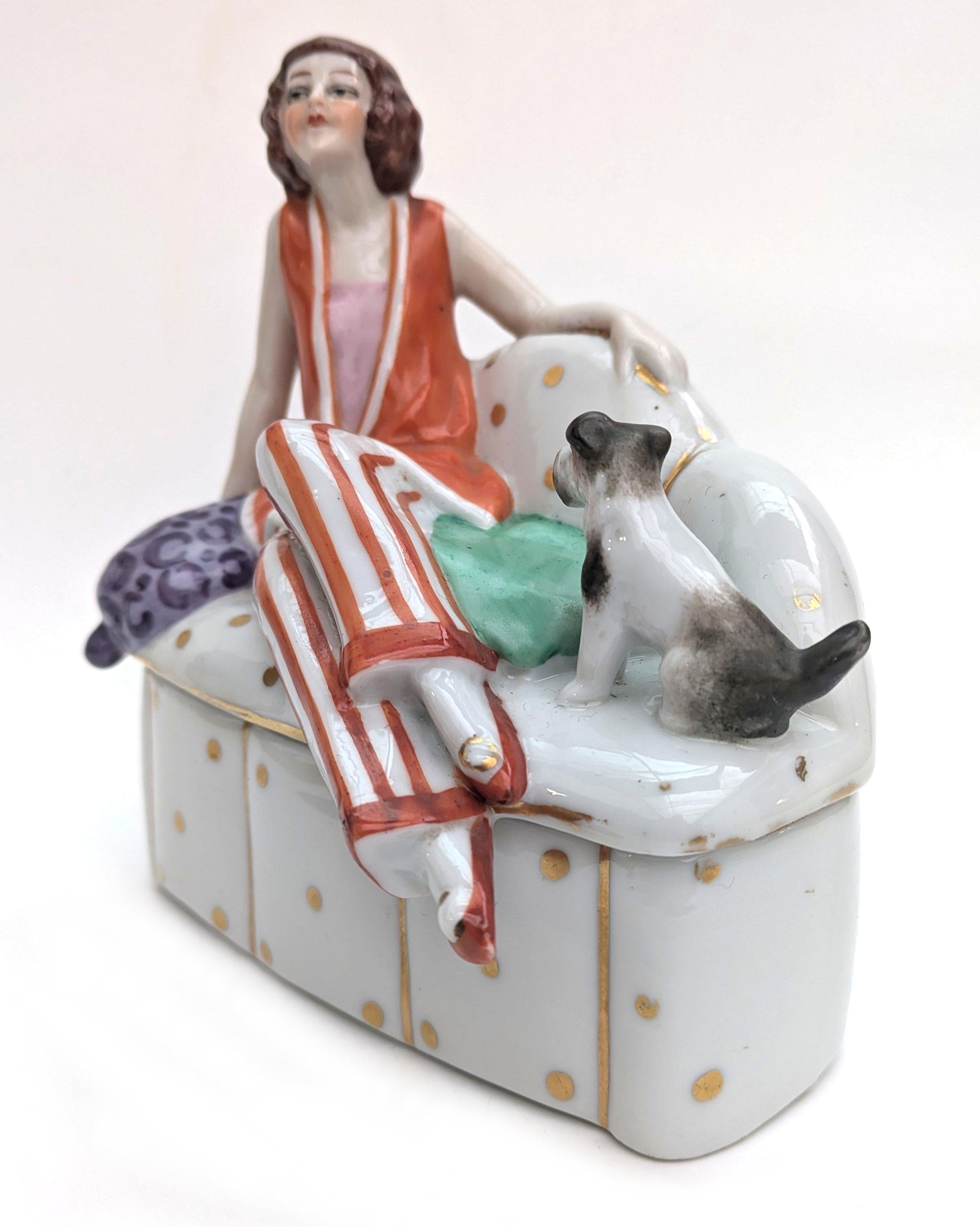Delightful and charming 1930's Art Deco ceramic powder box. Features a young lady in the fashion of the day with her pet dog. A rare design and highly sought after. The attention to detail is just wonderful, so skillfully painted, from her slightly