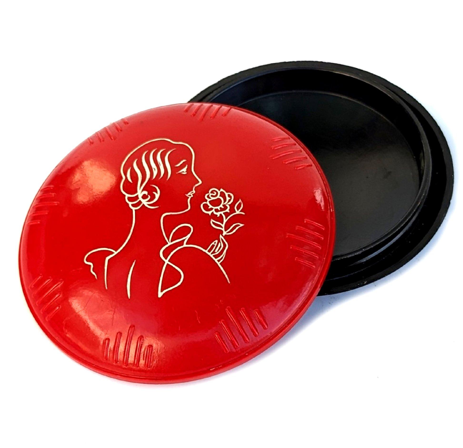 C'est fabuleux, on ne peut pas le confondre avec une autre époque, n'est-ce pas ? Il s'agit d'un poudrier en celluloïd pour dames datant des années 1930. Le couvercle représente une jeune femme à la mode. Le bord du couvercle est également gaufré.