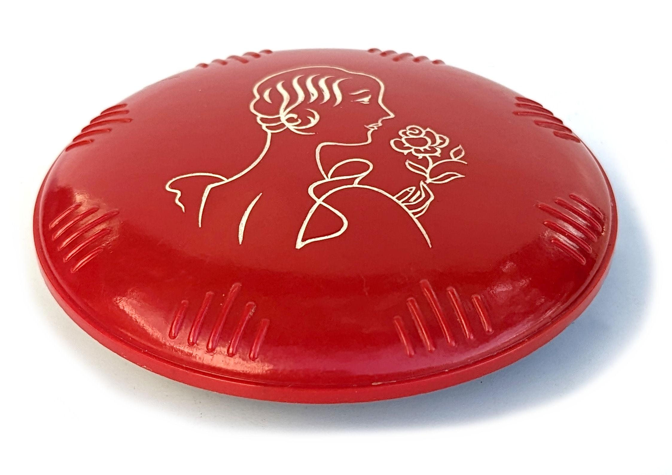 Early celluloid Art Deco ladies compact dating to the 1930's. Depicts a young flapper lady on the lid, the lid is also embossed around the edge. The pot itself screws together with the top. Super colourway of lipstick red and jet black with painted