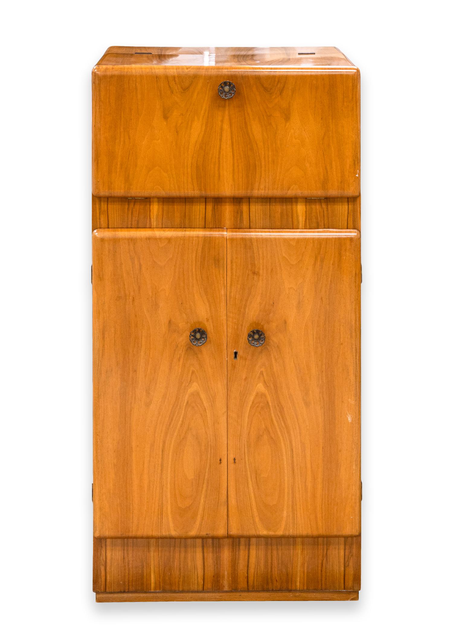 An art deco flip top dry bar. A beautiful piece from George Serlin for London based Sureline Furniture. This piece features a beautiful wood construction with a light wood color and gorgeous wood grain. The top cabient opens up and drops down to