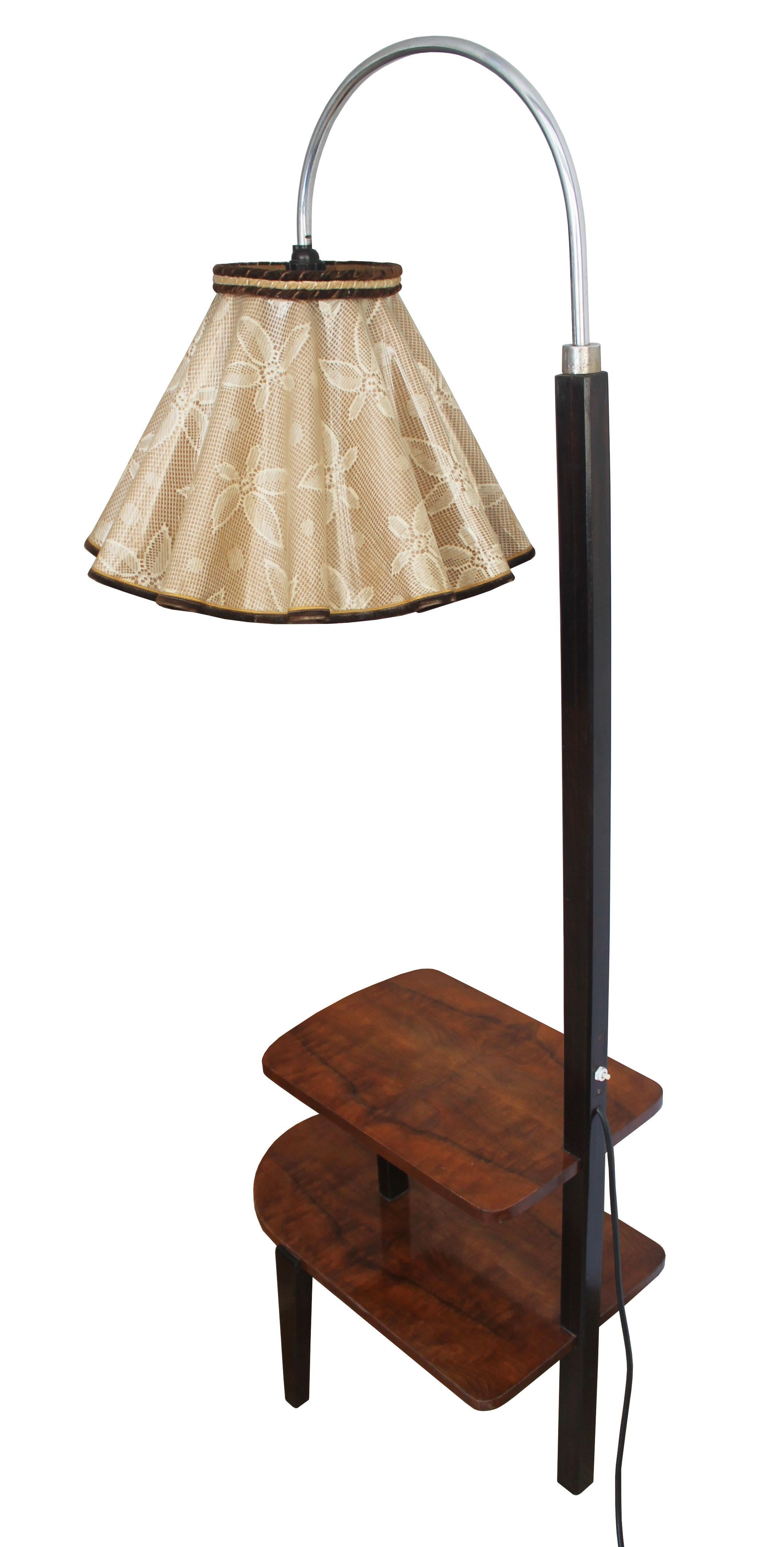 An Art Deco floor lamp with original lampshade and two low level shelves in great vintage condition. This lamp has got an subtle shape and a beautiful wood combination of walnut veneer, and dark beech together with a delicate floral pattern on the