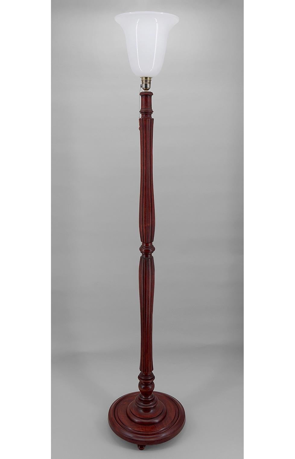 Magnifica lampada da terra da salotto di tipo Mazda in faggio tinto mogano, intagliata e scanalata. È sormontato da un diffusore in vetro (bianco opalino). 
L'interruttore si trova sulla presa, con una linguetta a strappo sulla presa, con piccole