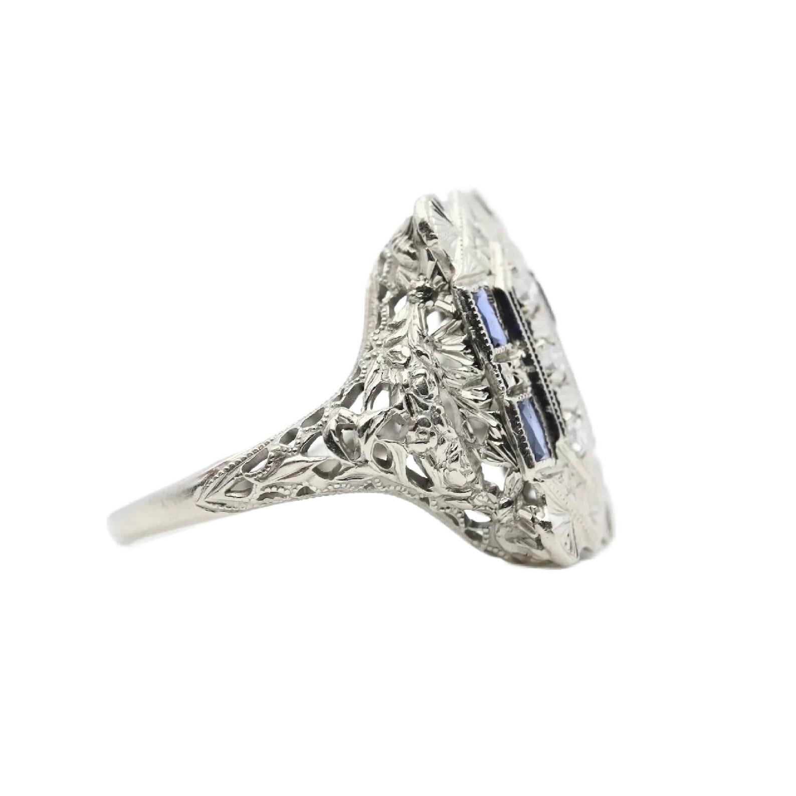 Ein filigraner Ring aus 18 Karat Weißgold mit Diamanten und Saphiren im französischen Schliff aus der Zeit des Art déco. In der Mitte befinden sich drei eingefasste Diamanten und vier Baguette-Saphire im französischen Schliff. Mit einem Gewicht von
