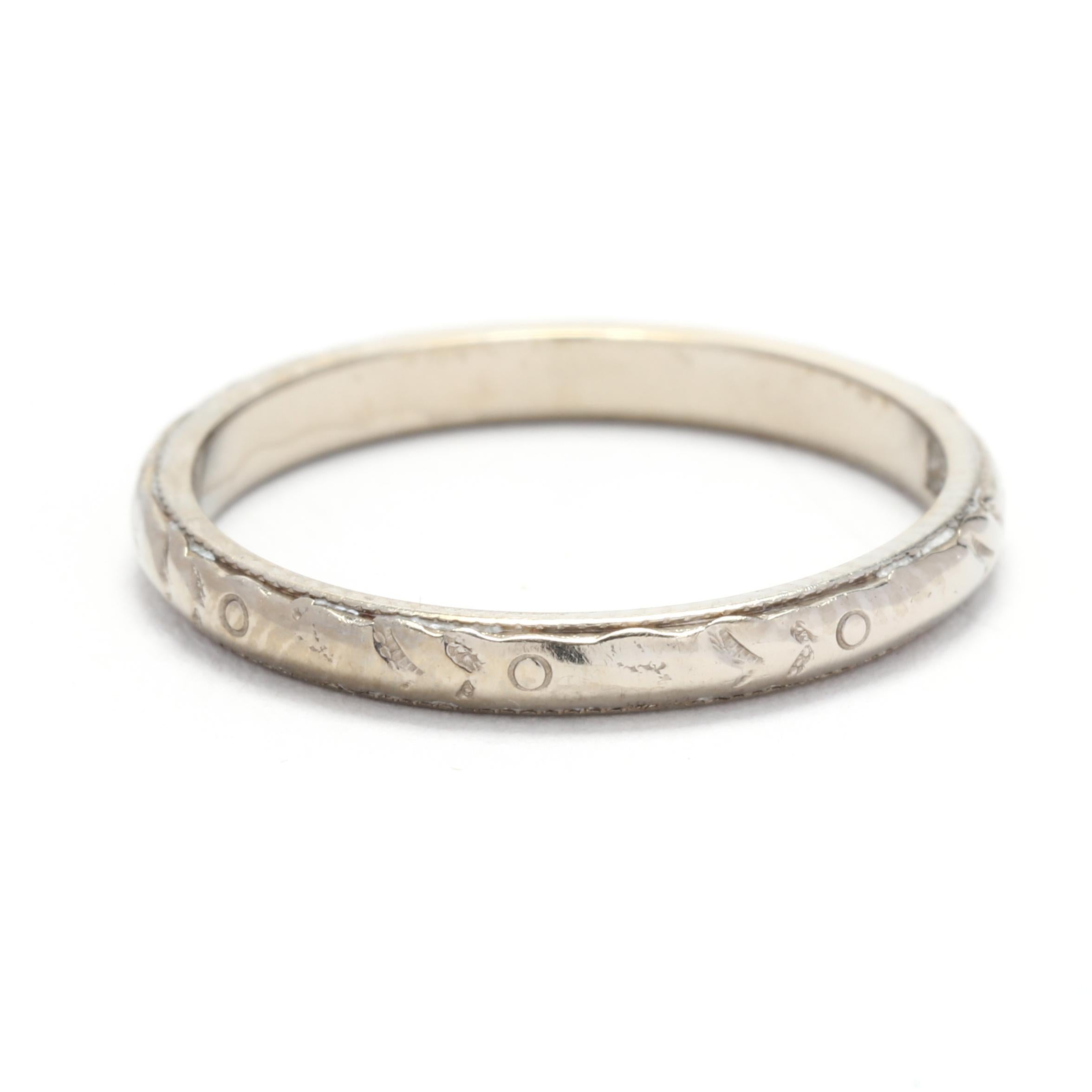 This stunning art deco floral engraved wedding band is crafted from 18k white gold. It features a delicate and intricate floral design that is both timeless and elegant. The band is a size 5.25 and can be worn alone or stacked with other rings for a