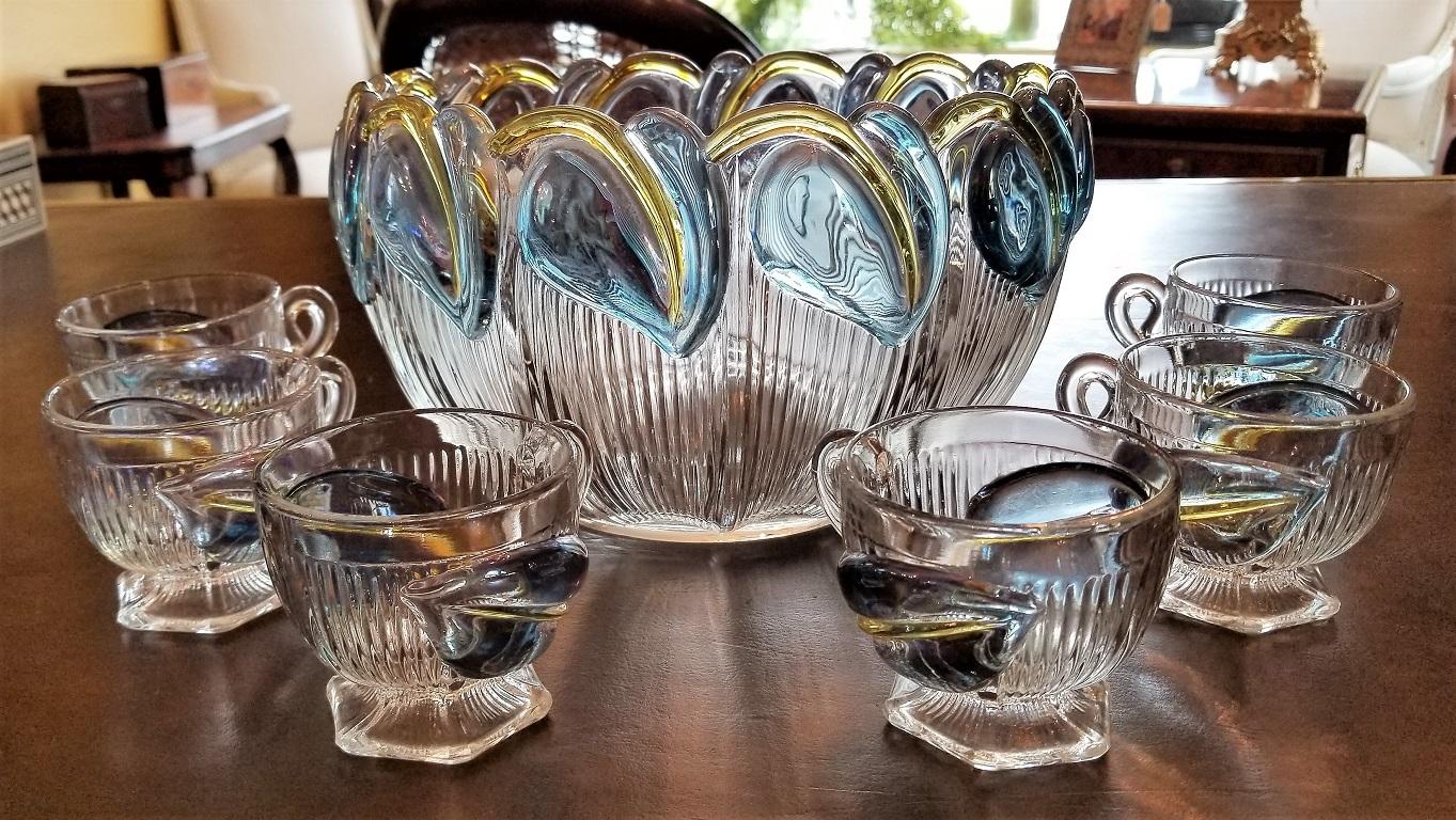 Presenting a very rare Art Deco floral punch bowl and 6 matching glasses from, circa 1925.

This punch bowl and matching glass set are made of molded glass and in a Classic Art Deco style and form.

The Bowl has ribbed sides with blue and yellow