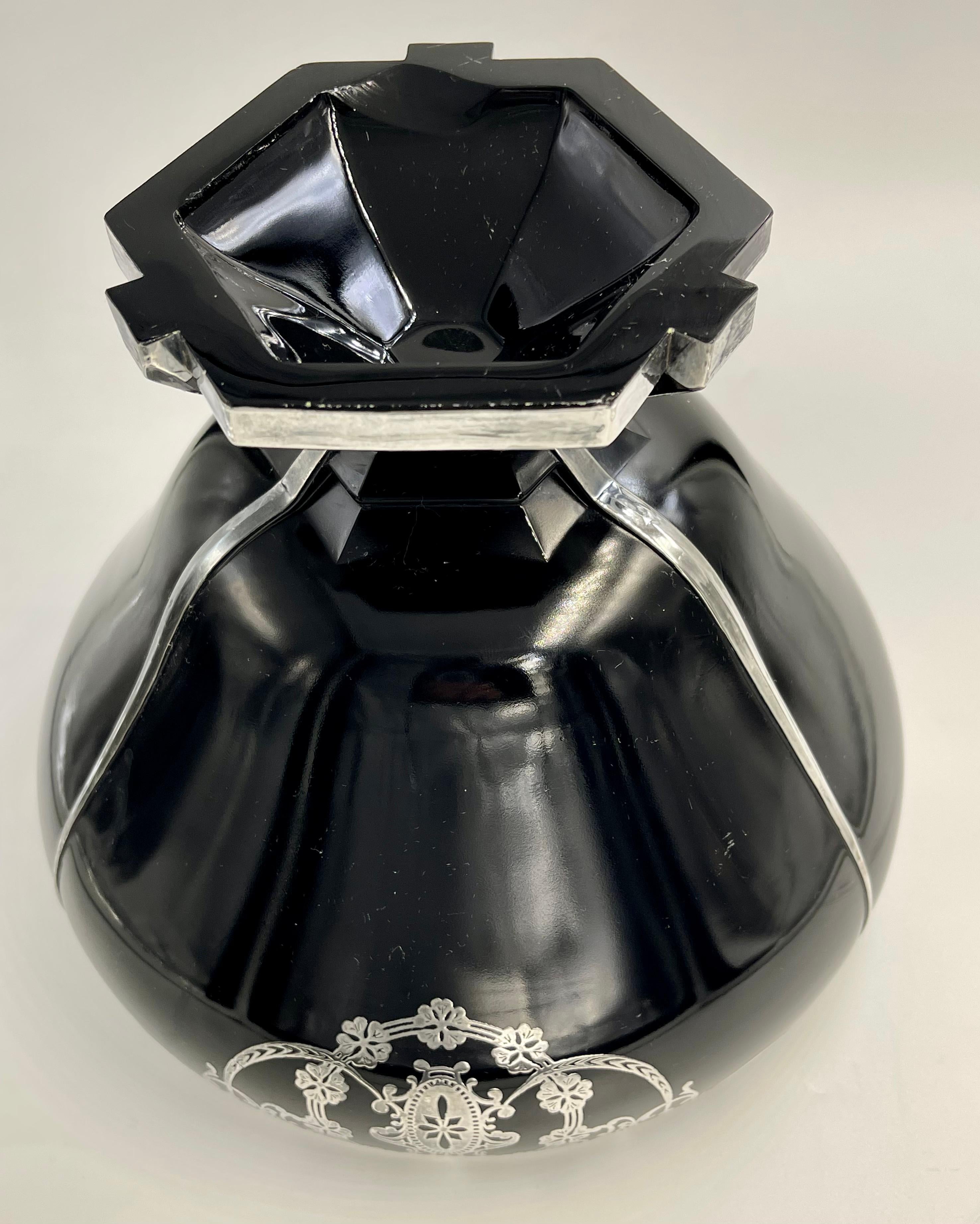 Impressive Art Deco black amethyst glass with a flower, vine, scroll and cartouche design in three areas going around the bowl near the top. The top has a sterling rim as does the bottom. There are also three sterling lines that run from the top to