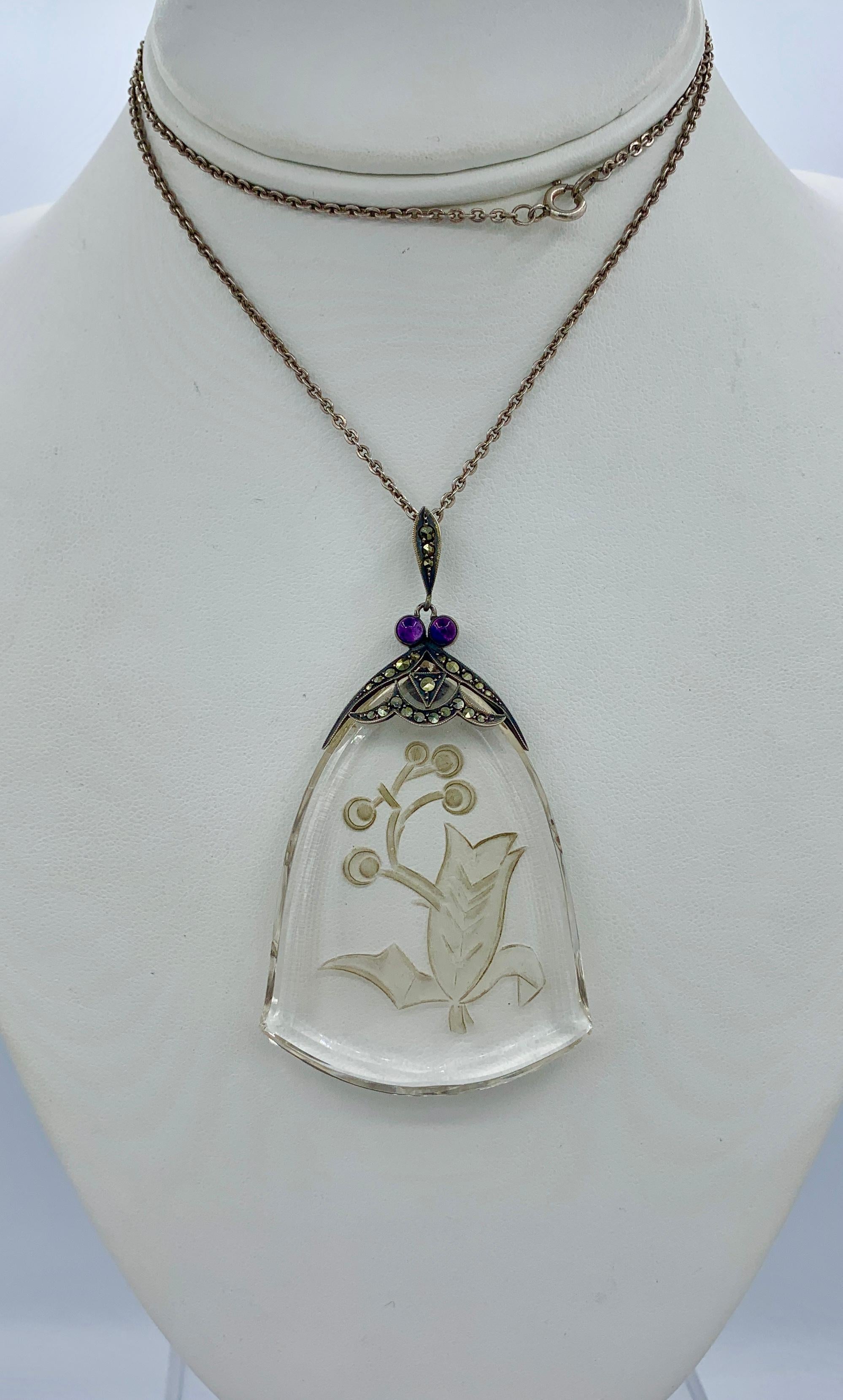THIS IS A WONDERFUL AND VERY RARE MUSEUM QUALITY ORIGINAL ART DECO PENDANT NECKLACE WITH AN EXTRAORDINARY FLOWER MOTIF CARVED ROCK CRYSTAL PENDANT SET IN A STERLING SILVER SURMOUNT WITH TWO ROUND AMETHYST CABOCHONS AND MARCASITES AND A MARCASITE SET