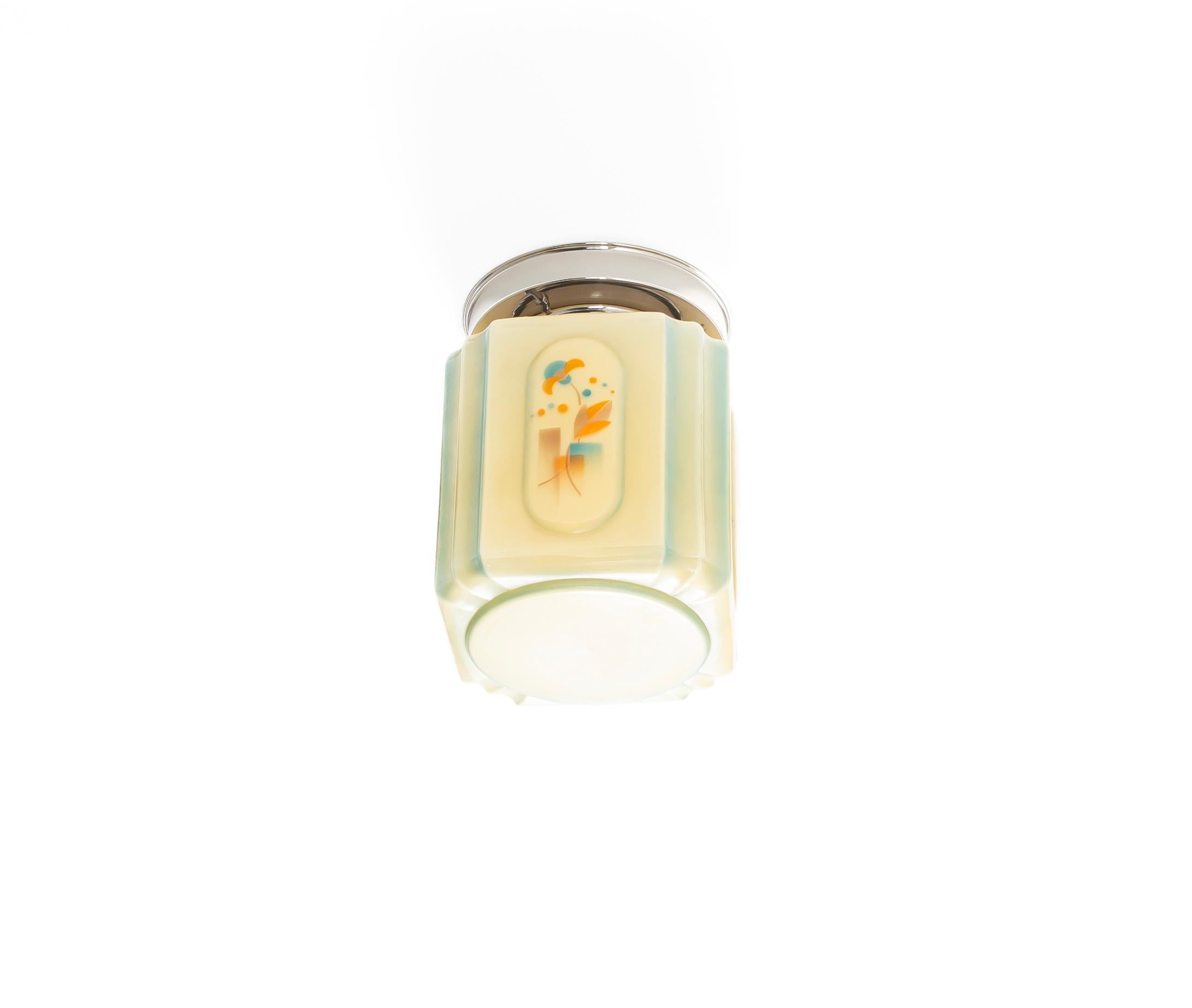 A beautiful art deco ceiling light fixture dating to the 1930s. This rare flush mount features a geometric silhouette, crafted from molded glass with soft cream and pale green tones that subtly shift under the light. Each of the four glass panels