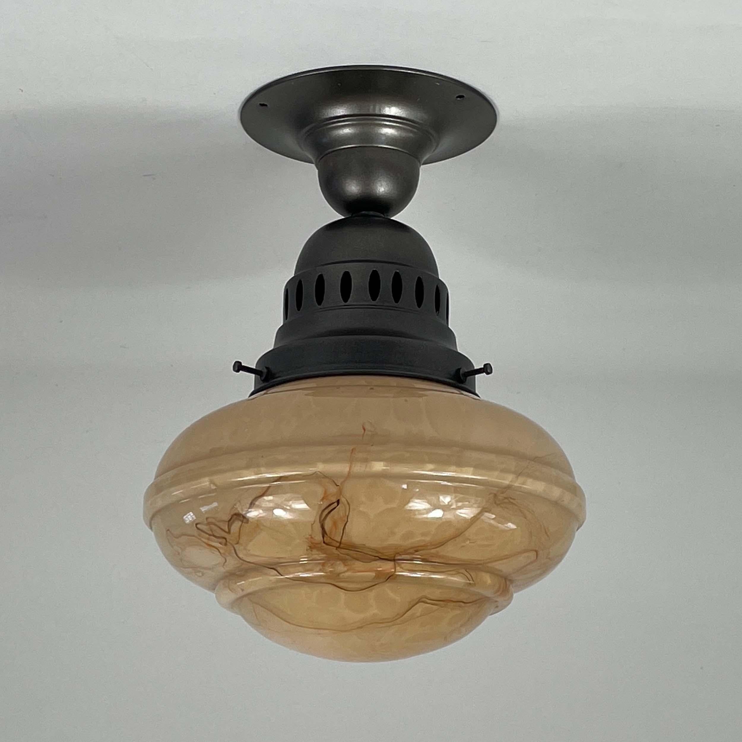 Diese Art-Déco-Unterputzleuchte wurde in den 1920er bis 1930er Jahren während der Bauhaus-Periode in Deutschland entworfen und hergestellt. 

Der Lampenschirm besteht aus opalem, dunkelsandfarbenem Glas mit einem marmorierten, gewirbelten Muster,