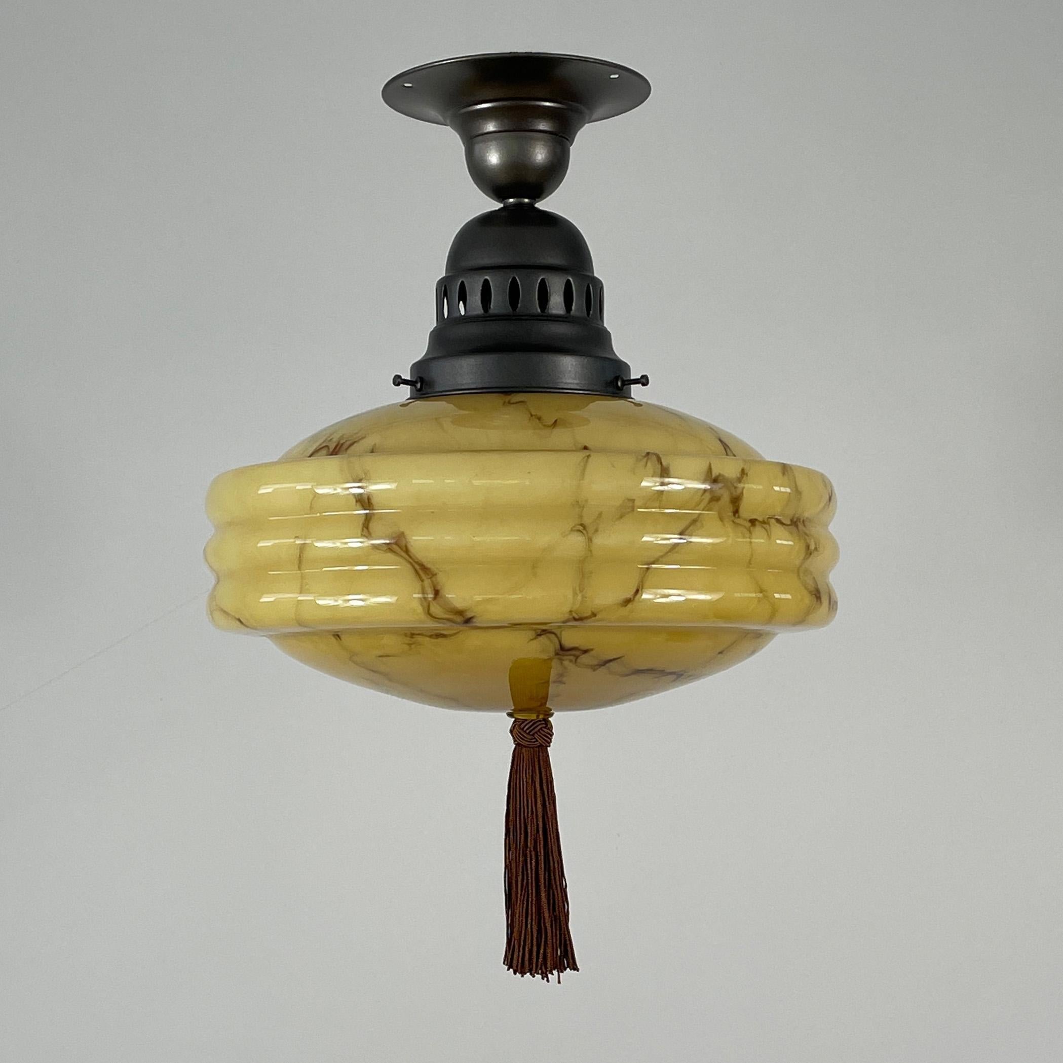 This elegant Art Deco flush mount was designed and manufactured in Germany in the 1920s to 1930s during the Bauhaus period. 

It features a sand colored opaline glass lampshade with marbled decor and stepped design and bronzed / burnished brass