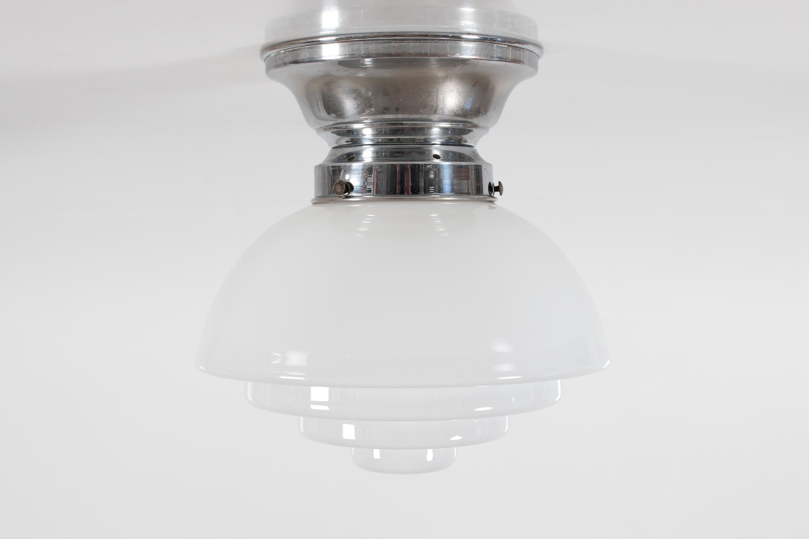 Art deco Bauhaus style flush mount from the 1930s made by Danish lamp manufacturer.

From a nickel plated base a stair-shaped dome of mouth-blown white opaline glass extend into the room.

 We recommend to use bulbs with a warm glow.

The lamp comes