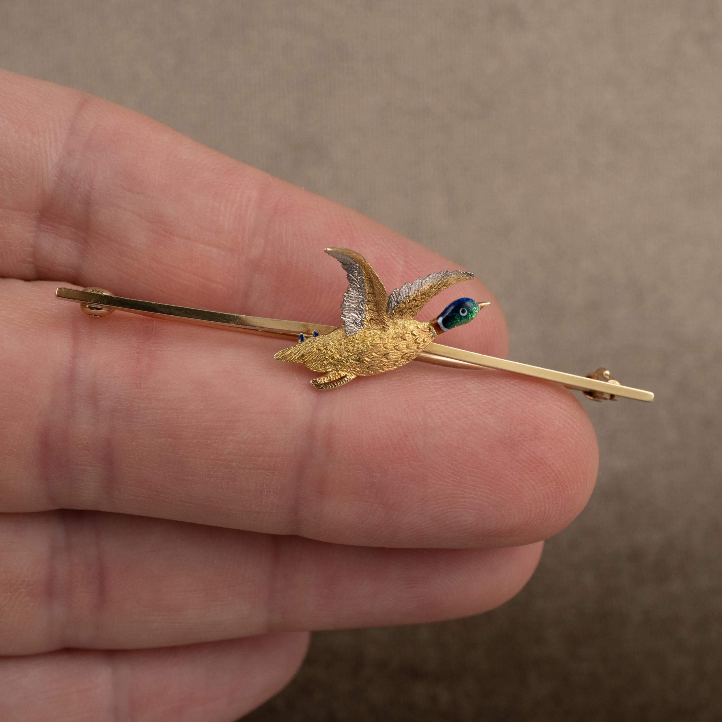 Art Deco 18K gold, platinum, and enamel flying Mallard duck brooch, circa 1930s.

The Mallard duck, shown in flight, has been beautifully crafted and shows fine detail to the body and wings. The gold wings are brushed complimenting platinum. The