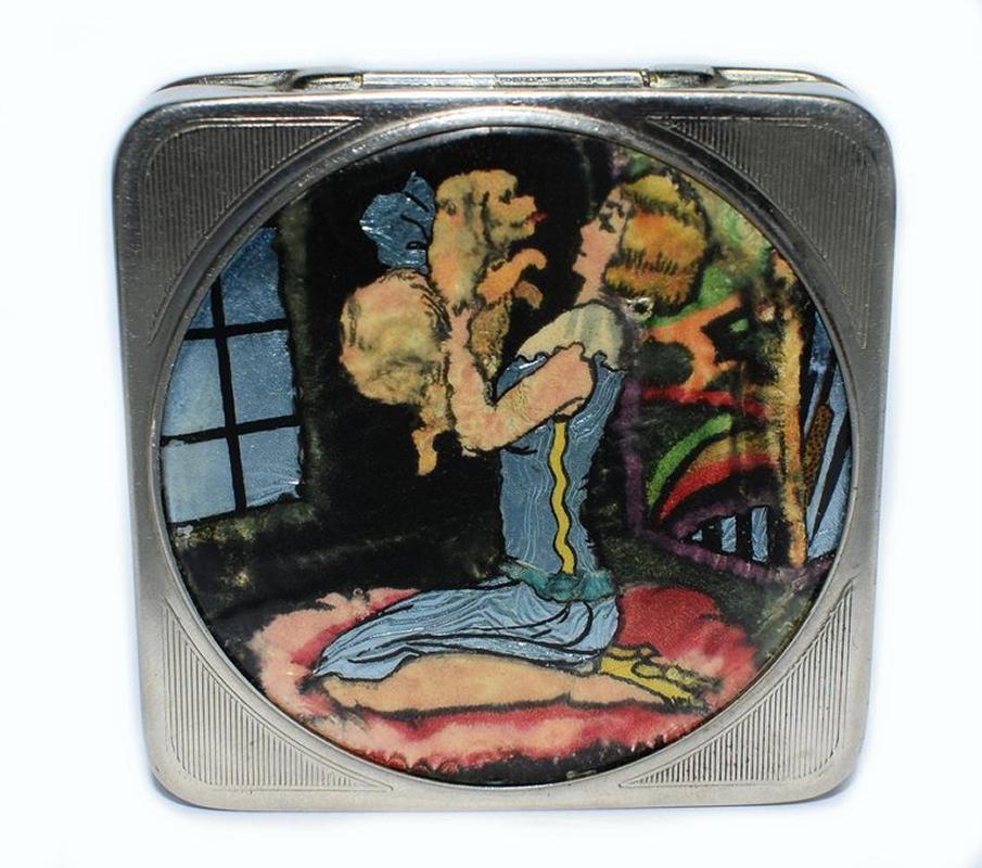 A delightful ladies Art Deco compact marked to the interior with the trade name Stratnoid made in England with the registration design number for 1931. The base is engine turned with the top lid depicting a wonderful scene of a young flapper girl
