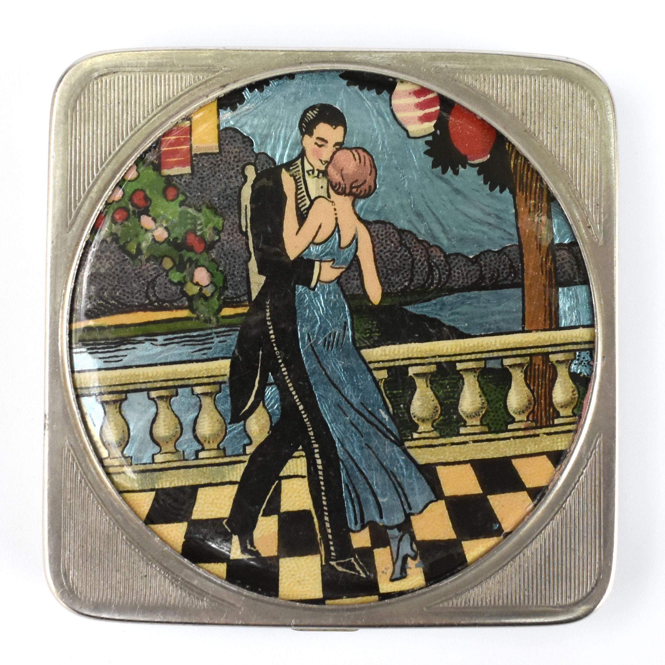 A delightful ladies Art Deco compact marked to the interior with the trade name Stratnoid made in England with the registration design number for 1931. The base is engine turned with the top lid depicting a wonderful scene of a young flapper lady in