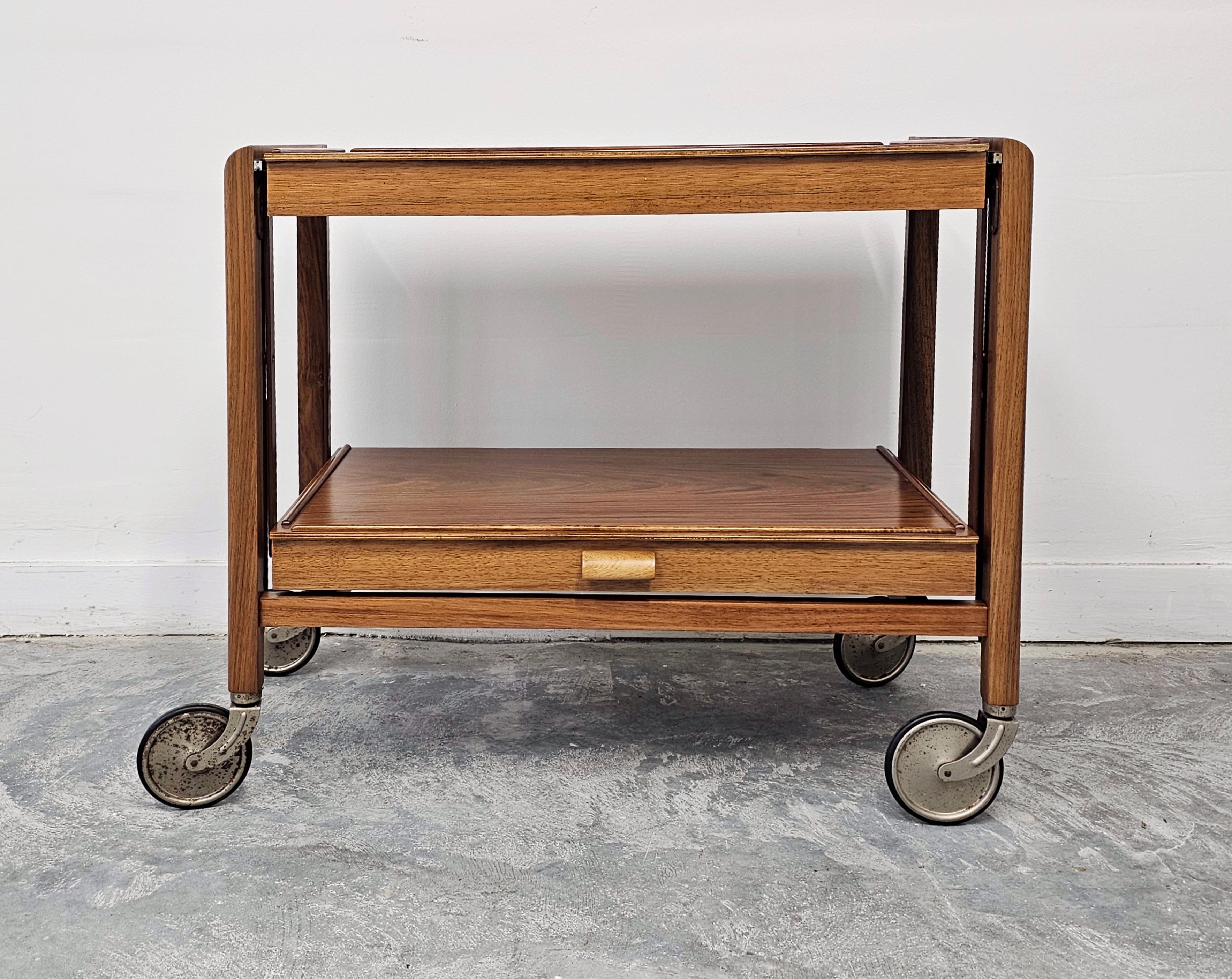 In questo annuncio troverai uno splendido e rarissimo tavolo da cocktail o carrello da bar pieghevole in stile Art Déco. Questo tavolo a due livelli si trasforma da carrello a tavolo semplicemente tirando il piano inferiore, per scoprire il