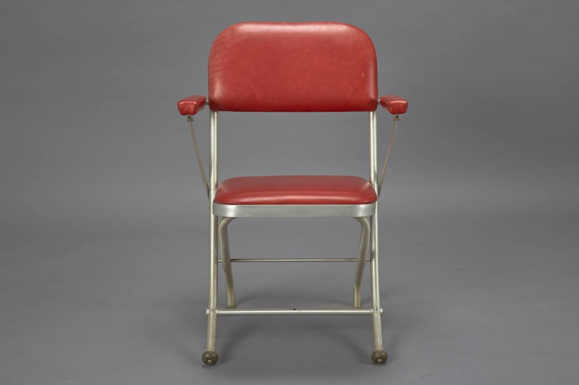 These Art Deco style Mid-Century Modern folding chairs were designed by Warren McArthur and manufactured by Mayfair Industries. They are constructed of tubular aluminium and feature red leather upholstery.
