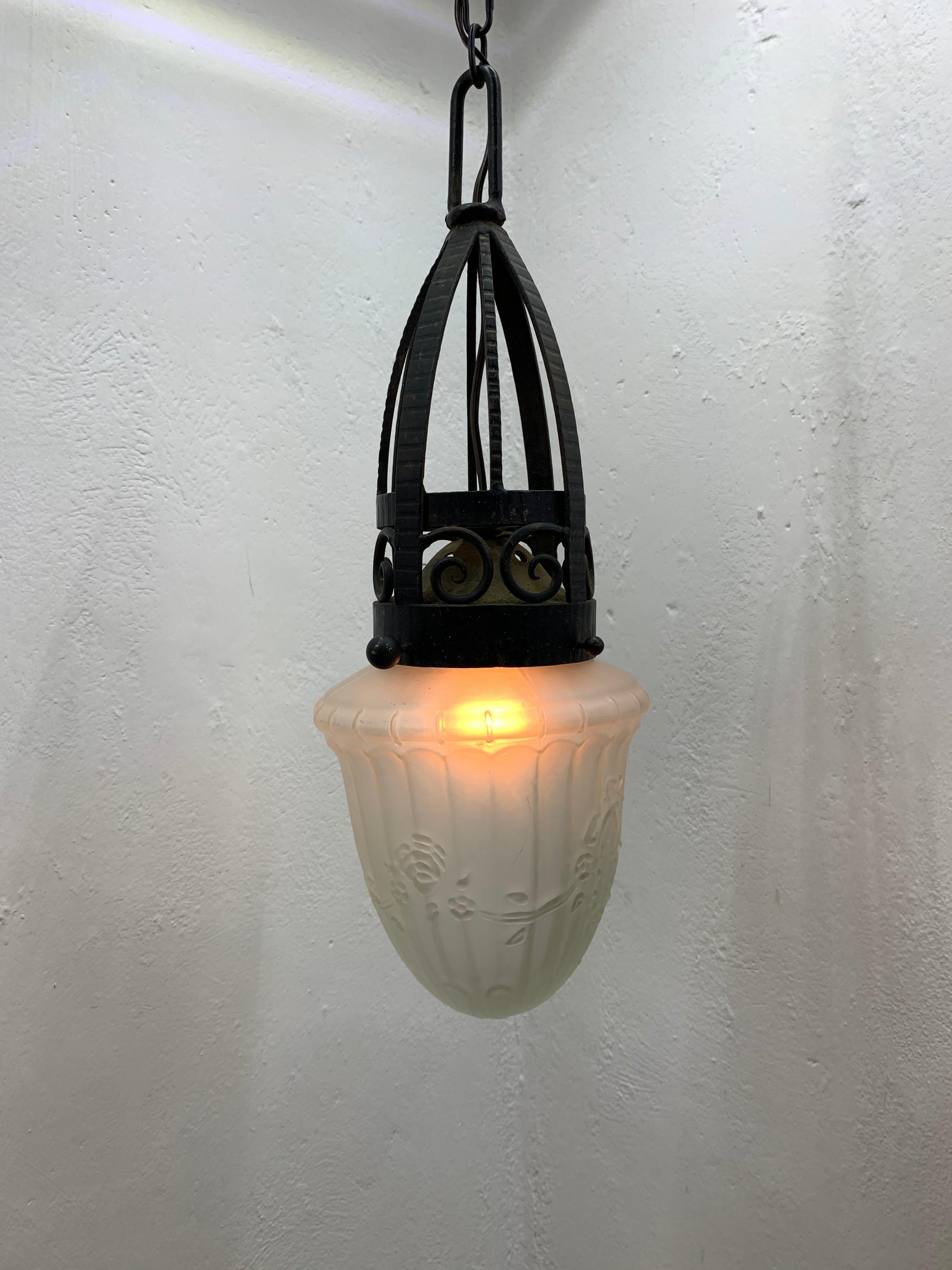 Art Deco wrought iron pendant light or lantern in the style of Edgar Brandt with a pressed glass globe.
The iron has its original black finish and shows its age, this can be cleaned and re-painted if desired by the customer.
France, circa 1930.
The