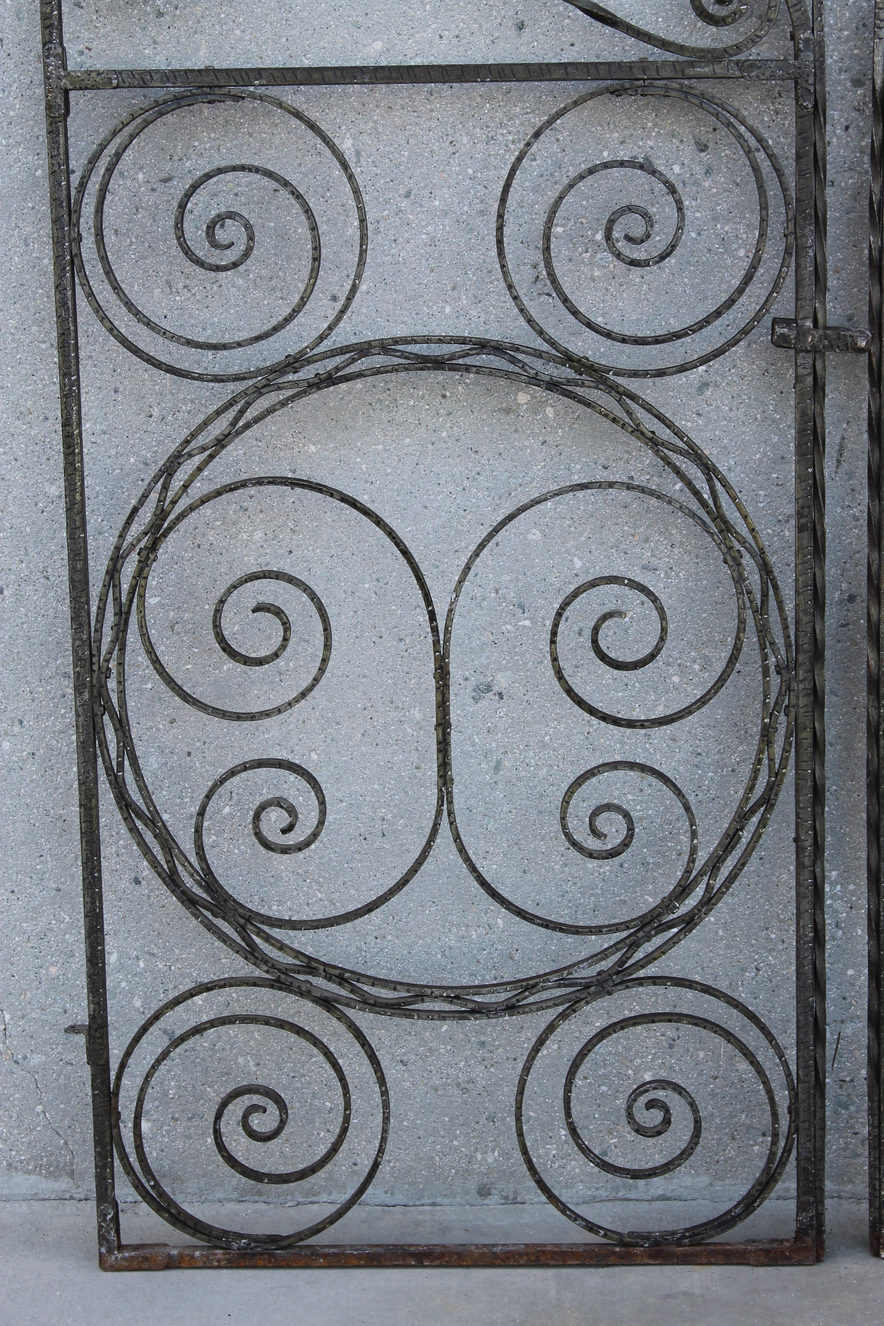 A large pair of Renaissance style forged iron gates with hand hammered and twisted scrolls and circles. Gates are evocative of Erte butterflies of the 1920s. Very detailed craftsmanship. Each panel is 27.5
