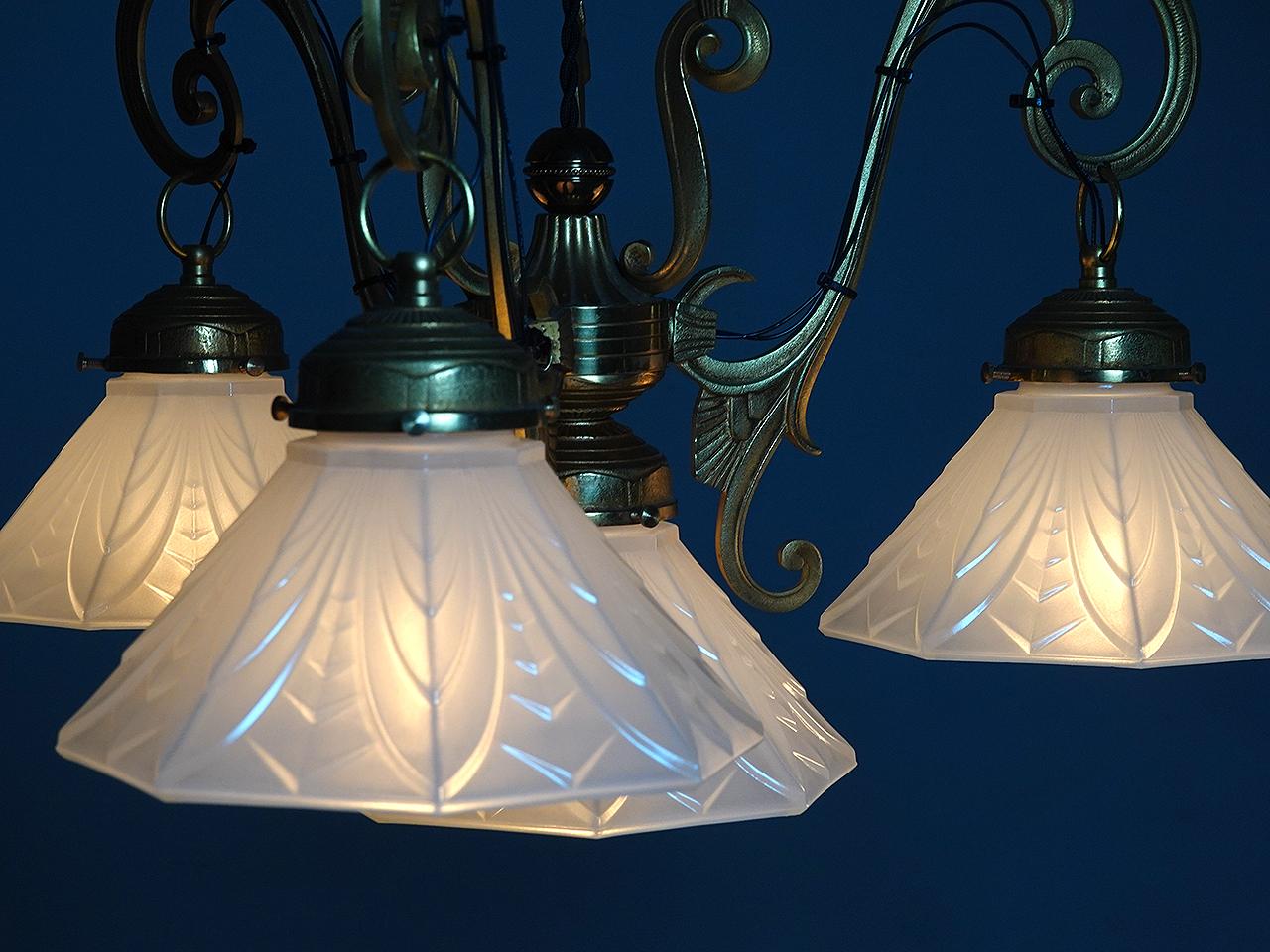 This is a nicely detailed deco chandelier. The shades are opaline with a subtle irradiance and a deco designs. The hight can be altered to your specs. There are four octogan shades and each have a 7 inch diameter.