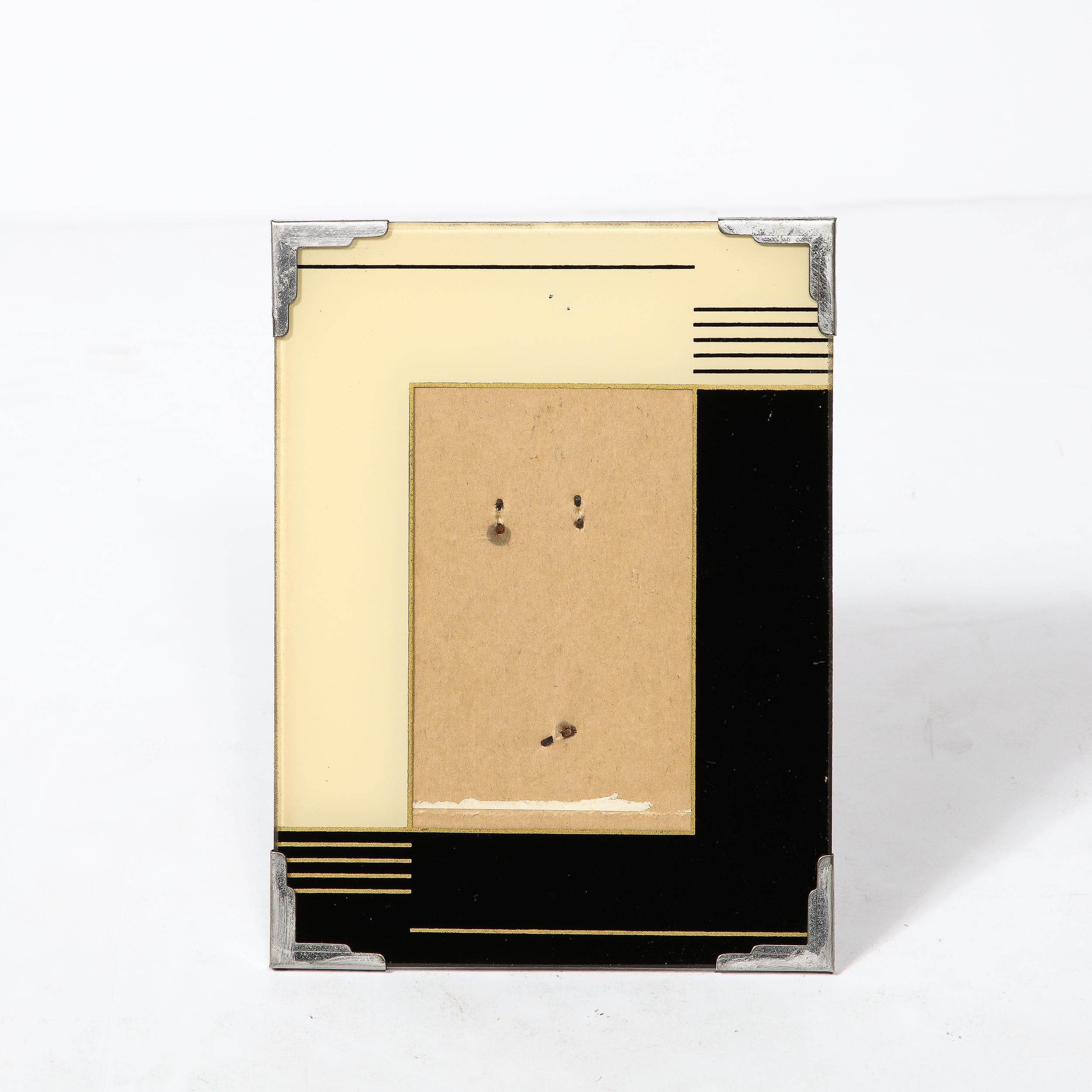 A beautiful small scale Art Deco picture frame from the United States, circa 1930. Fabricated in reverse painted glass  with streamlined chrome corners, the front panel features linear geometric detailing over interlocking background colors in black