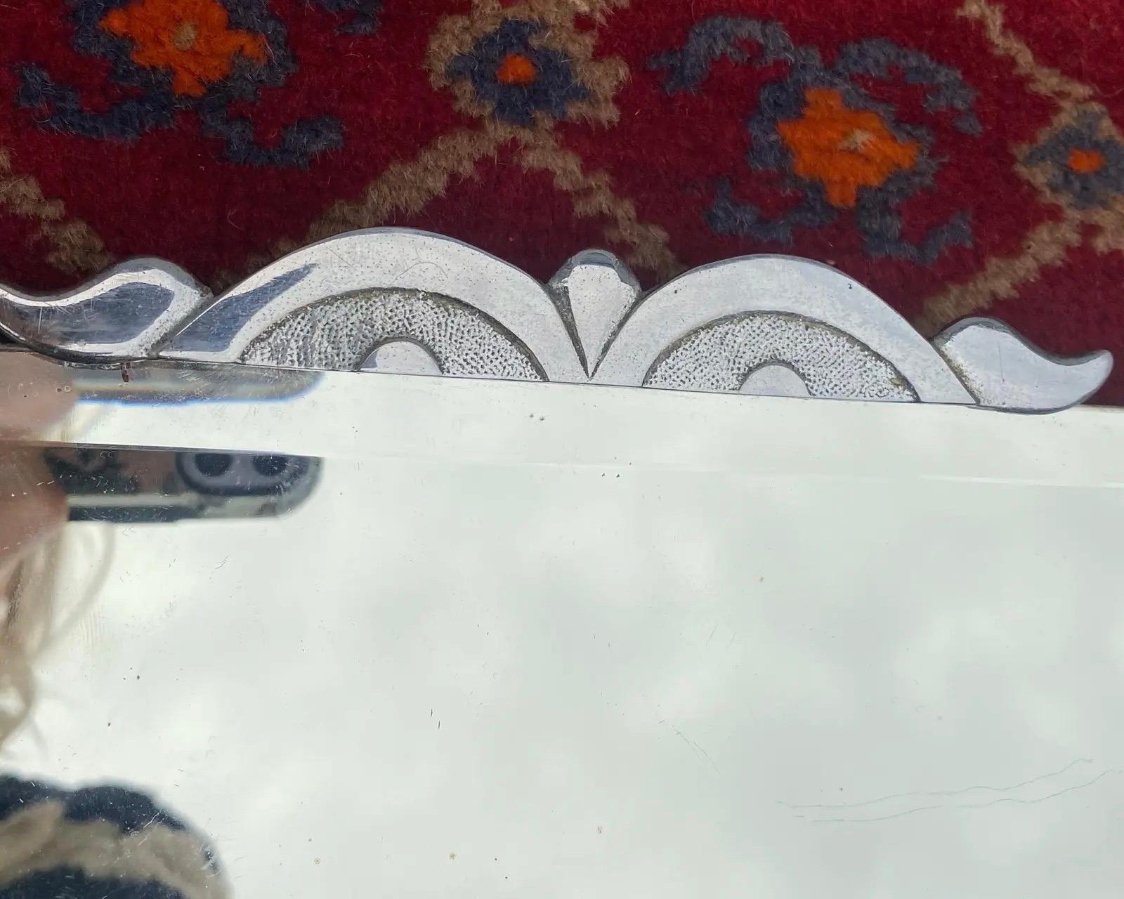 This mirror has a beautiful crest on top with some patina under the glass. 
Glass pain itself is hardly aged with very little patina and some very light marks on it. 
Minor marks and the most beautiful metal clasps holding the bevelled glass in
