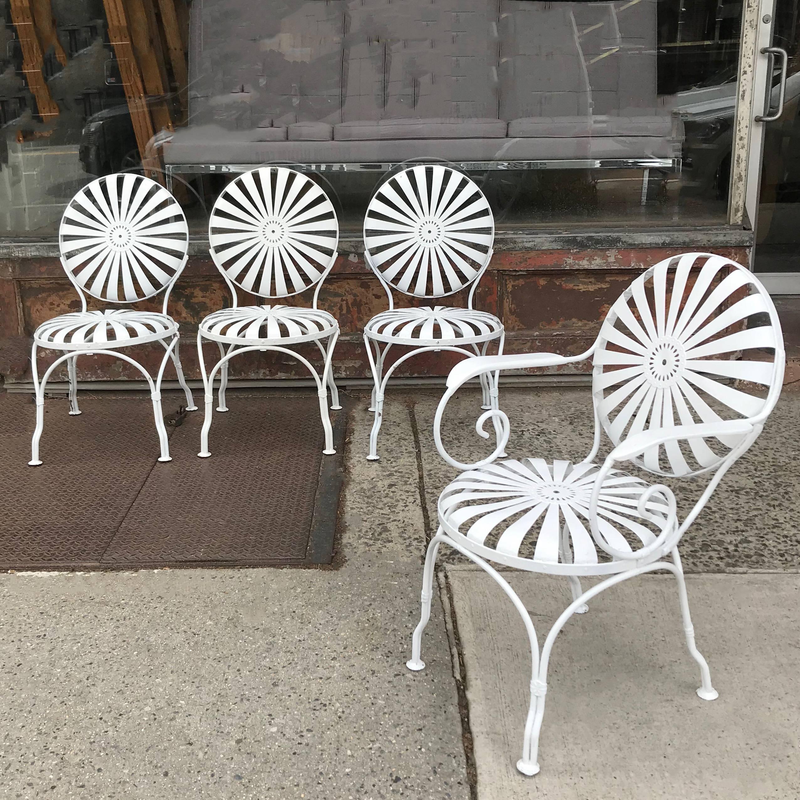 Set of four, Art Deco, garden, patio, outdoor chairs by Francois Carré feature painted wrought iron, sunburst seats and backs. The set includes three side chairs that are 18.5 inches wide and one armchair.