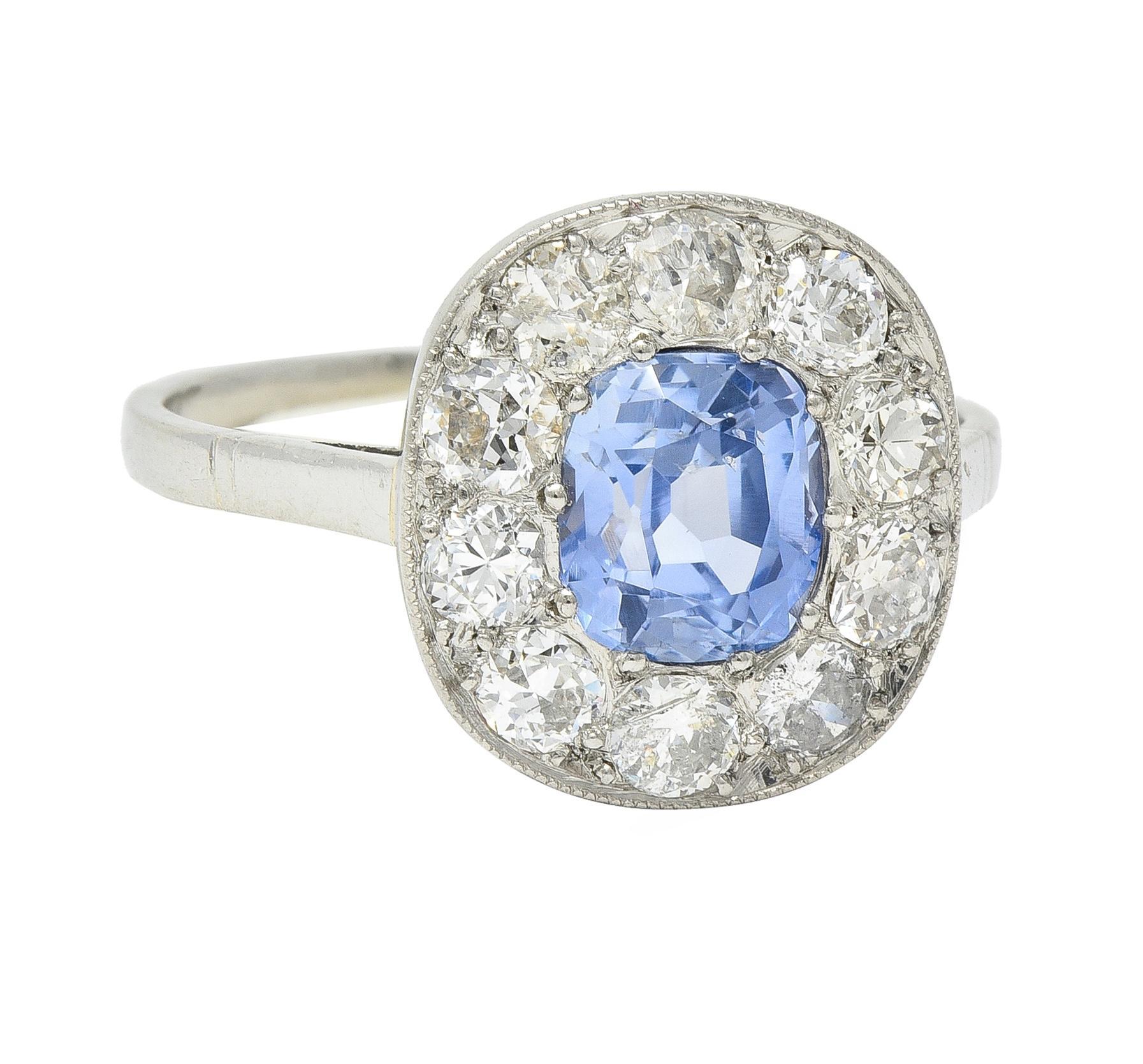 Centering a cushion cut sapphire weighing 1.33 carats - transparent light cornflower blue 
Natural Sri Lankan in origin with no indications of heat treatment - bead set 
Featuring a halo surround of old European and transitional cut diamonds