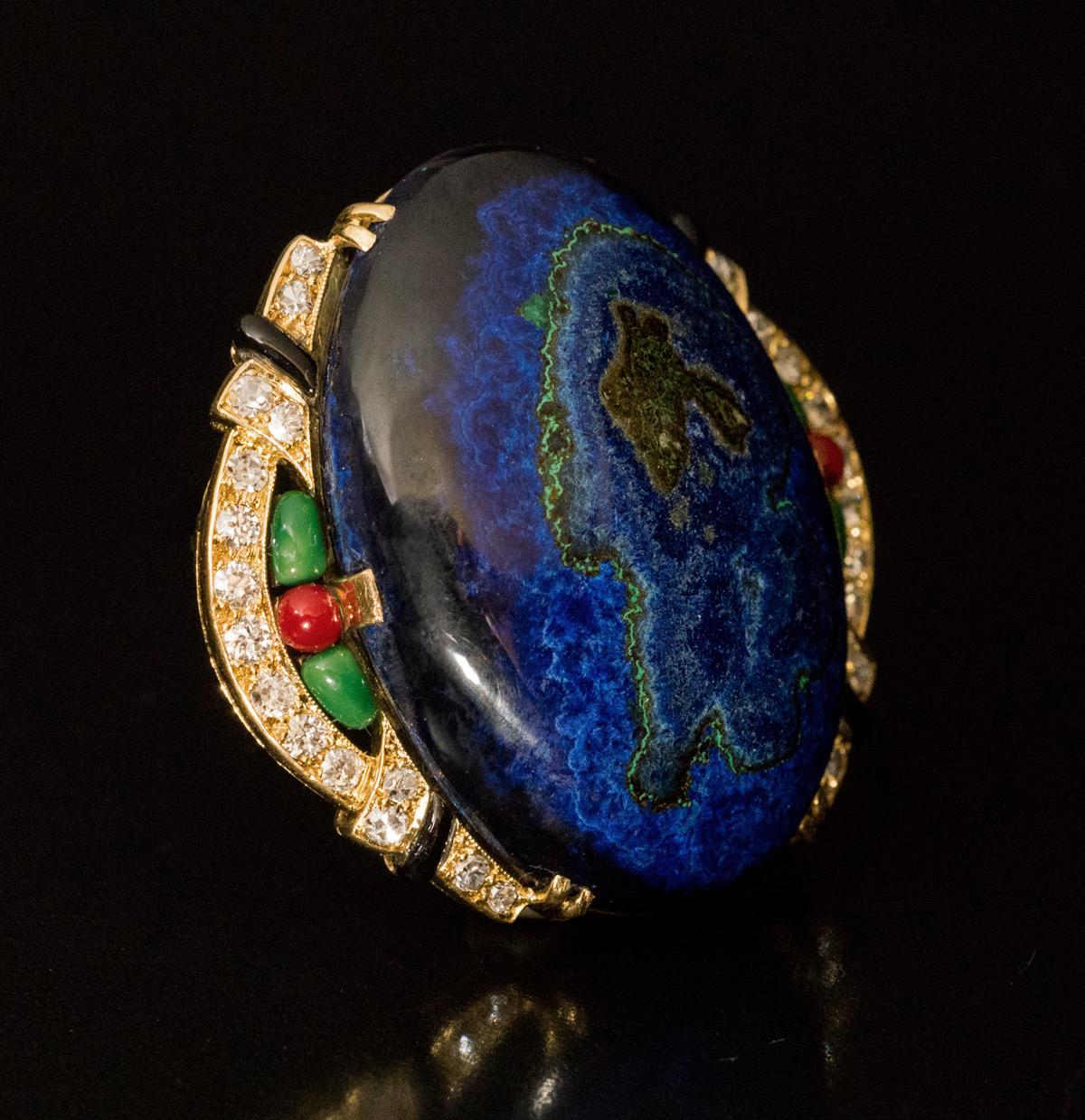 Circa 1925

This remarkable vintage French Art Deco brooch / pin features an oval cabochon cut azurite malachite set in an elaborate, slightly asymmetrical 18K gold bezel.  The bezel is embellished with bright white old cut diamonds (F-G color, SI