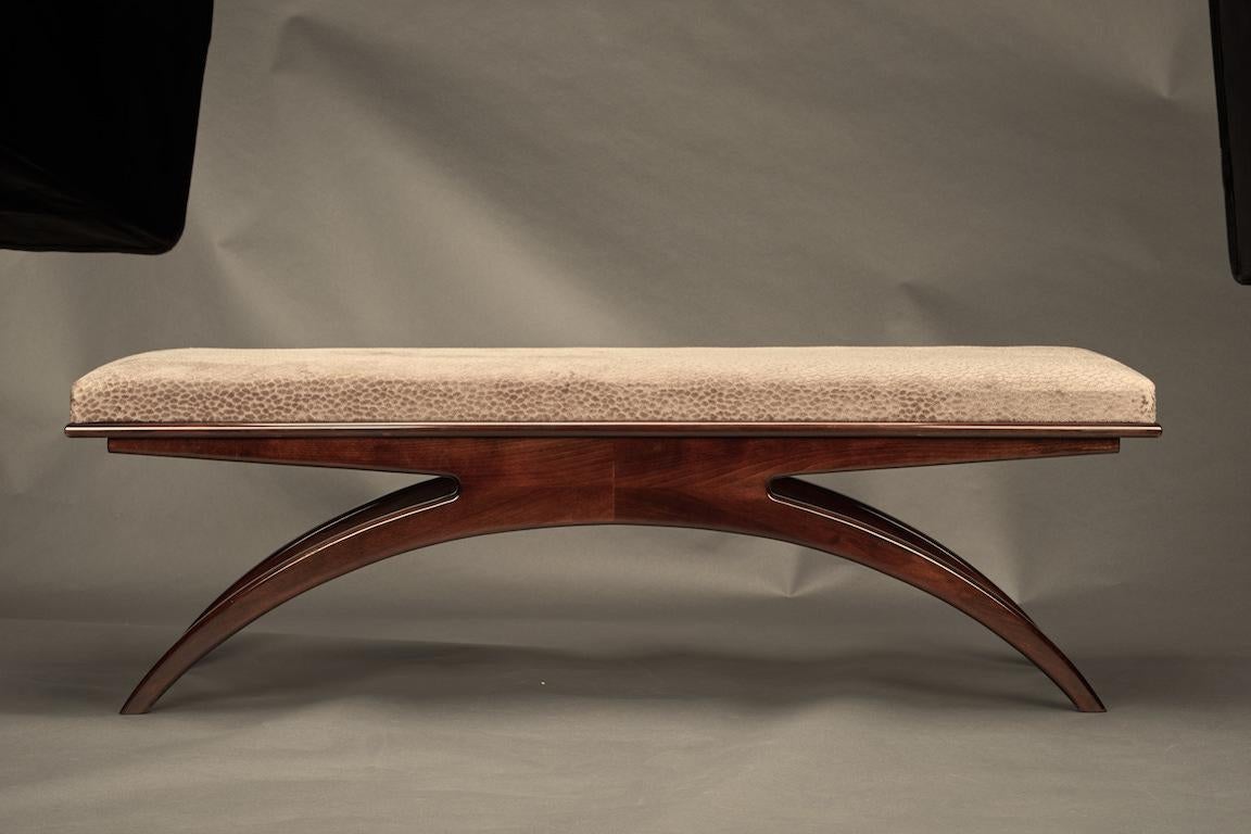 Art Deco bench is made out of walnut wood. Sit is newly re-upholstered in a light grey fabric. It supported and elevated by the 4 semi-curved legs, where 2 legs on each side are connected with each other, creating crescent shape. 
Condition is