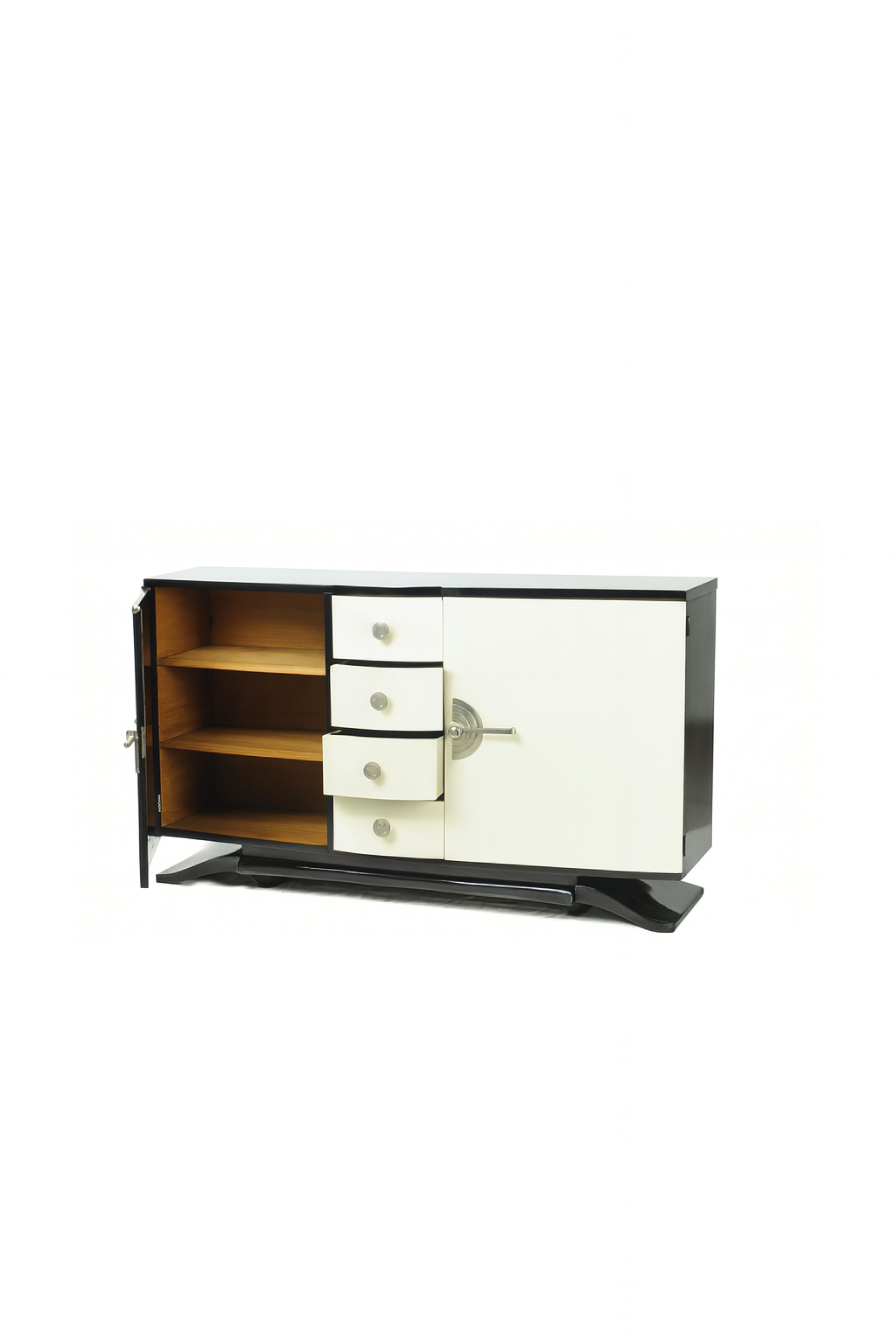 Una grande credenza Art Deco degli anni '40 presenta una notevole rielaborazione in bianco sporco e una rifinitura in colore nero. Ha un interno spazioso in cedro con due porte e quattro cassetti per stoviglie e posate. Il pezzo è impreziosito da