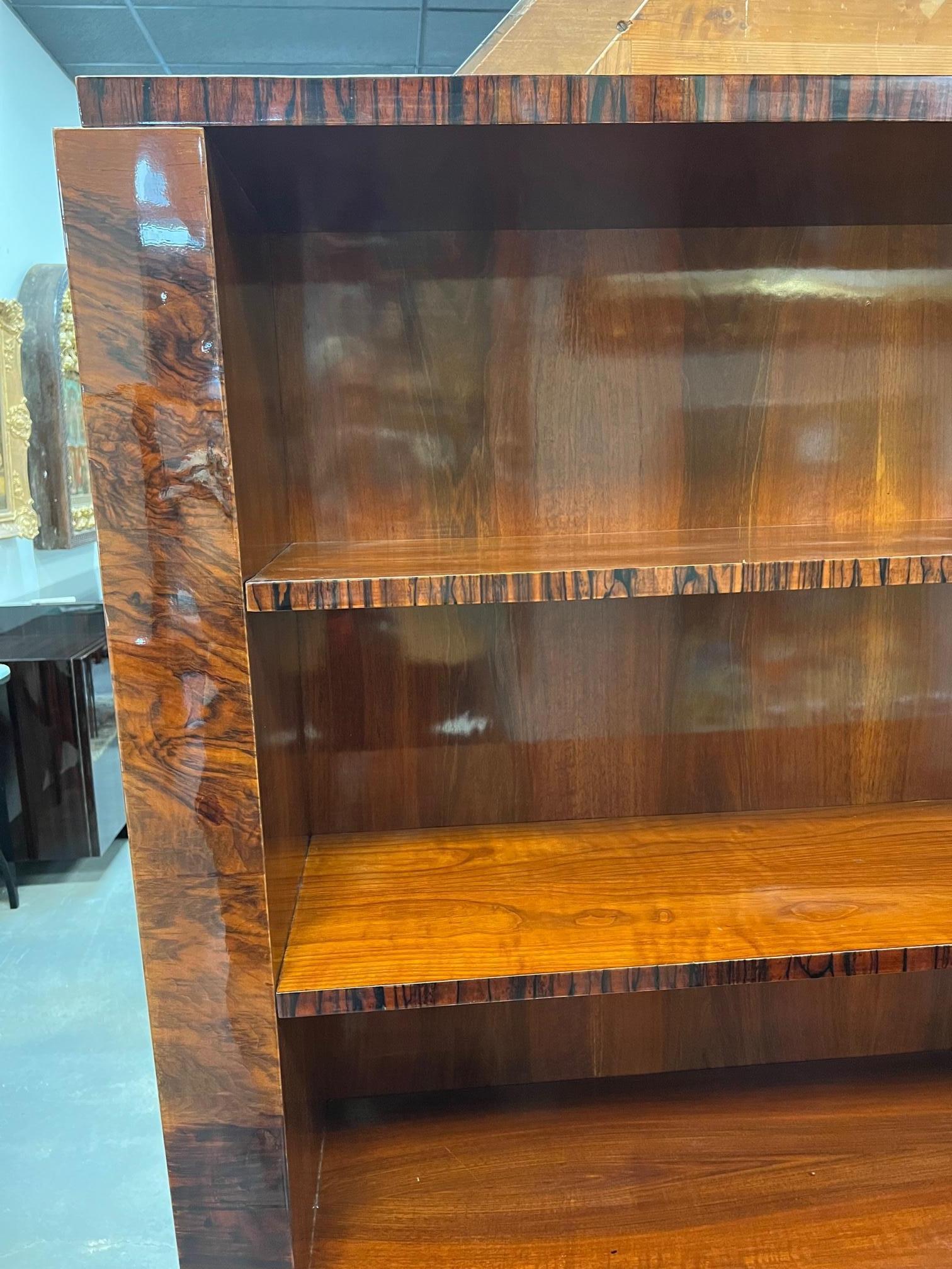 Art Deco Book case/ credenza. There are 3 big shelves and multiple little shelves and drawers with silver handles on the lower part of the bookcase. It rests on 2 wide legs. Bookcase is made out of walnut wood and Burl Walnut. 
Condition is very