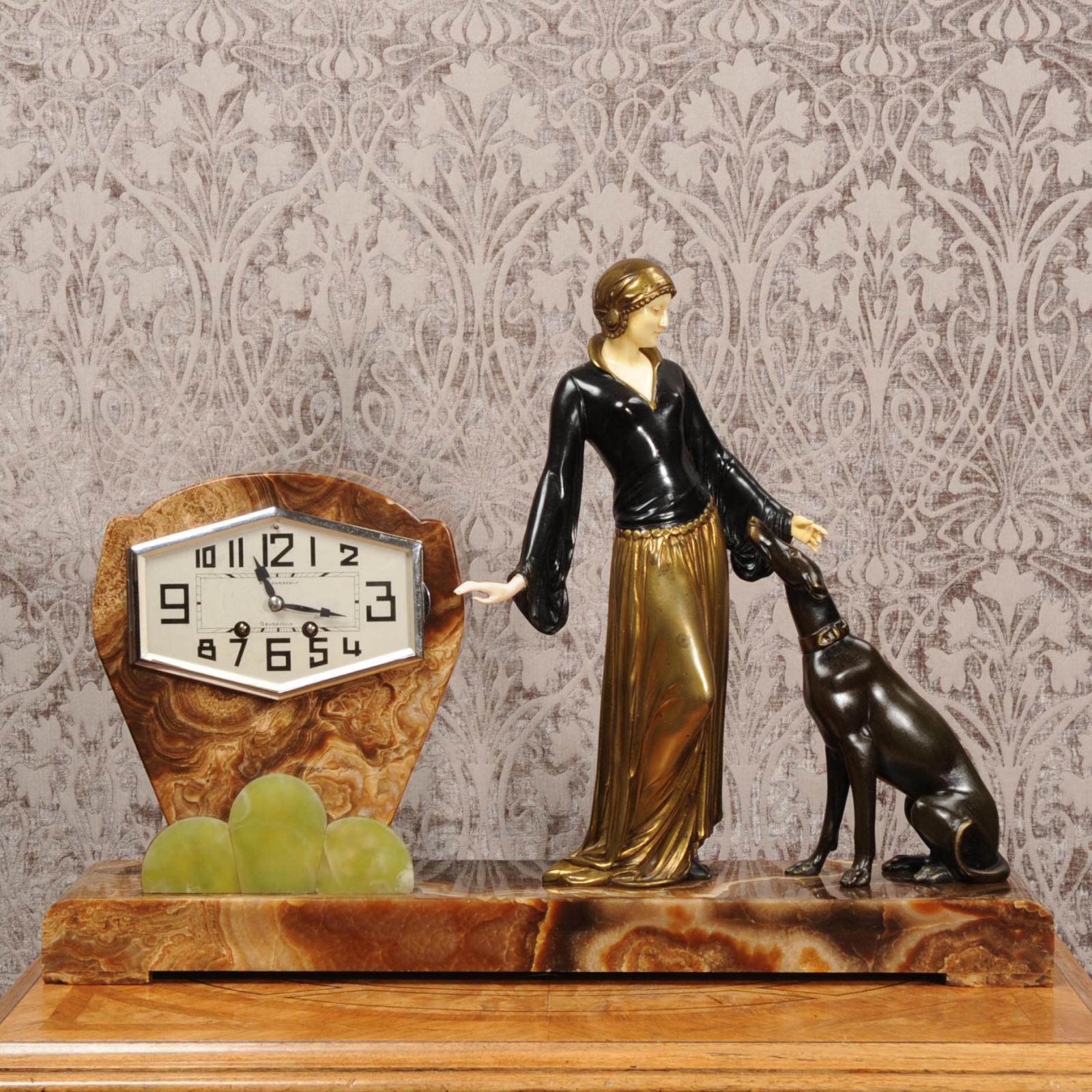 A large and superb Art Deco clock by Menneville (Urgo Cipriani), circa 1930. It features a stylish lady with her greyhound, standing beside the clock. She is modelled in patinated metal and her hands and head are delicately modelled in cream ivorine